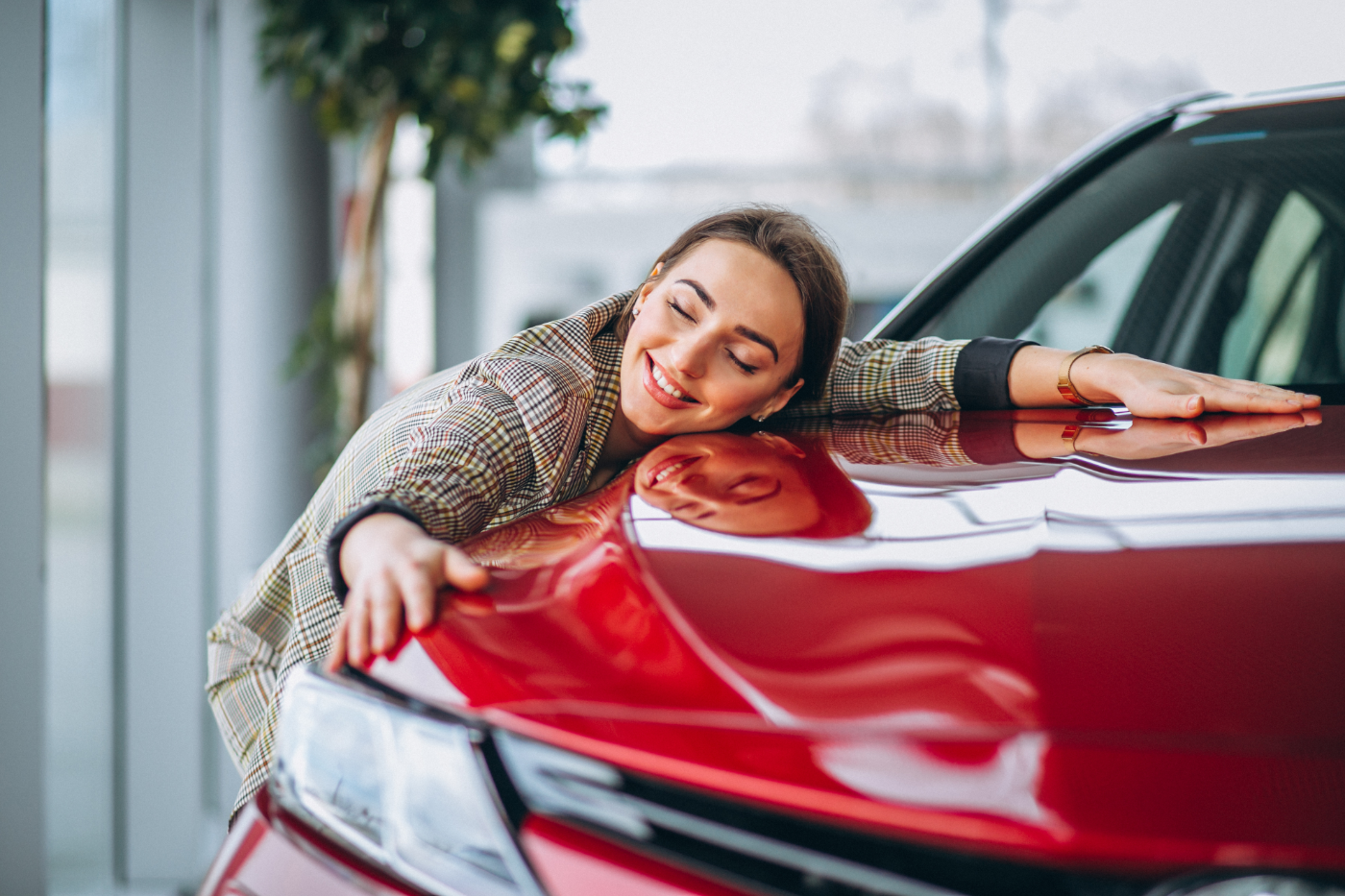 Young woman leaning on the hood of a car