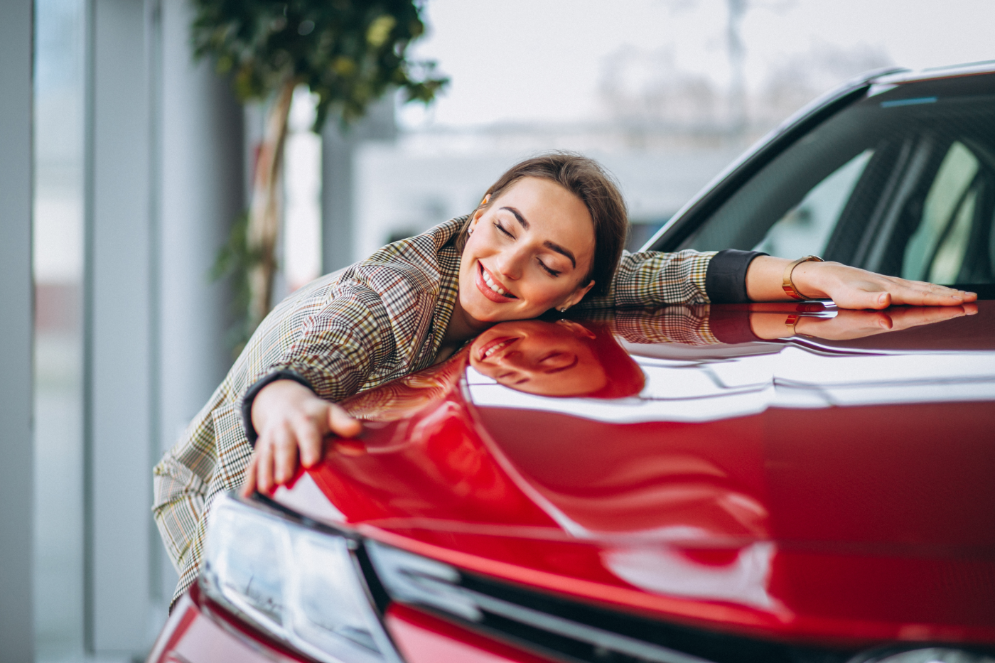 Eine junge Frau liegend auf der Motorhaube eines Autos