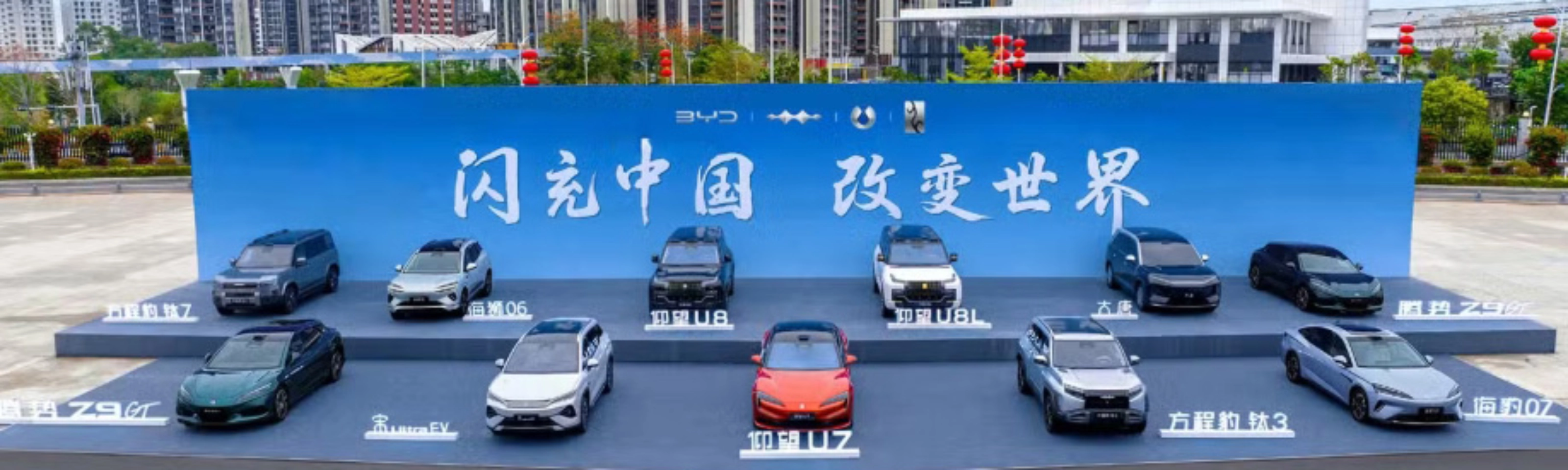 BYD vehicles displayed on a stage outdoors in front of a large promotional backdrop.