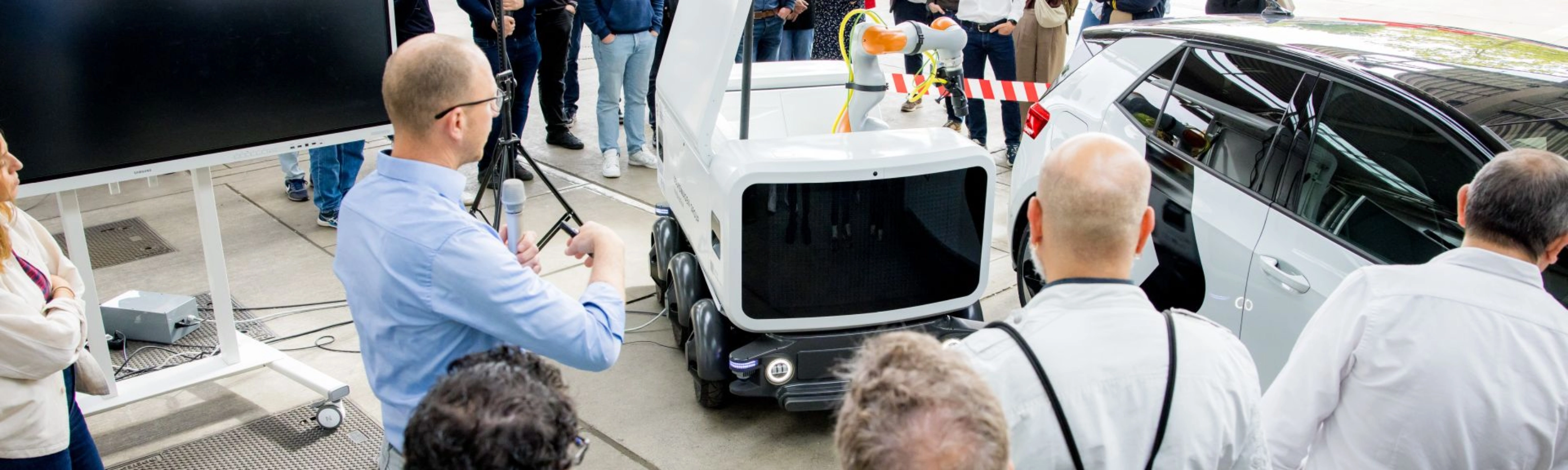 Group of people watching a Volkswagen vehicle demonstration at an outdoor event.