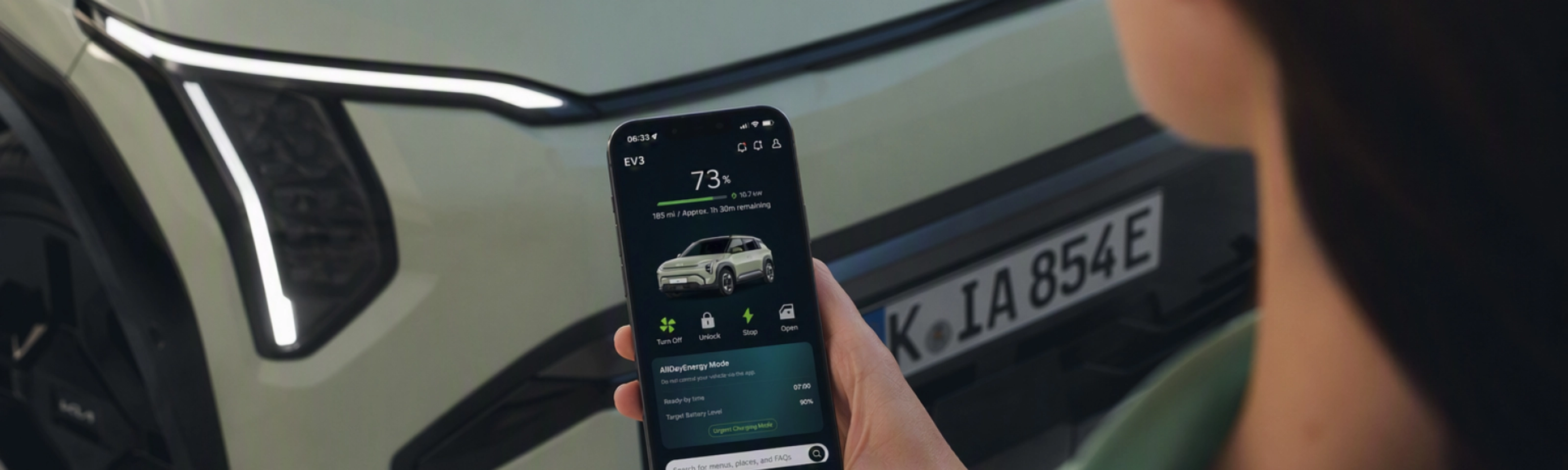 Person nutzt ein Smartphone vor einem Kia-Elektroauto