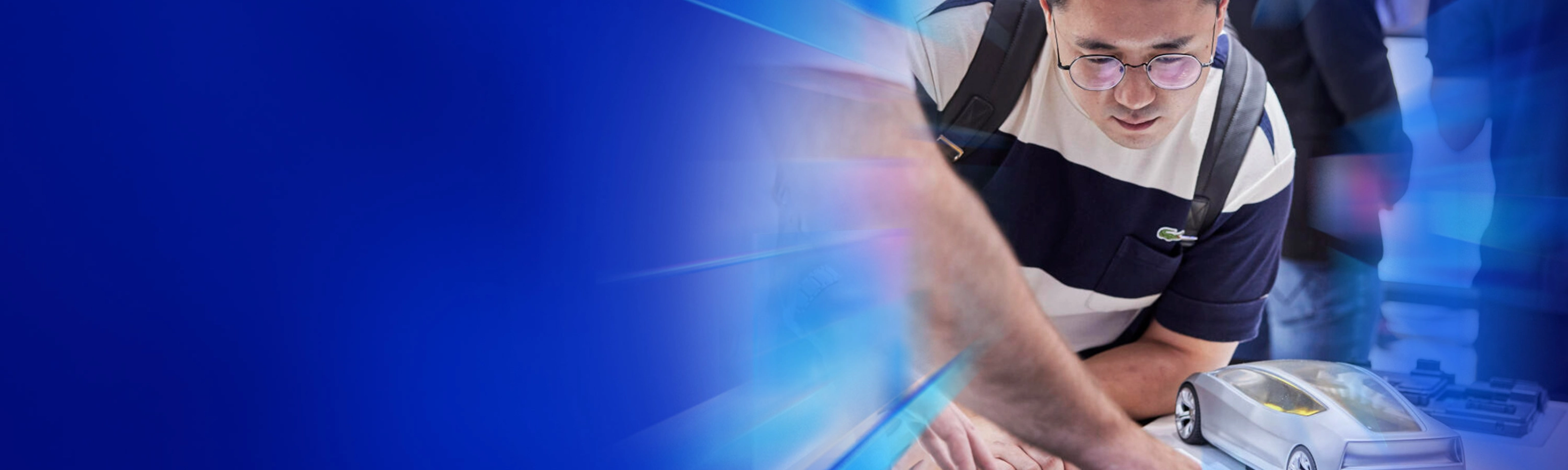 Mann betrachtet ein futuristisches Automodell und einen Touchscreen auf einer Technologiemesse.