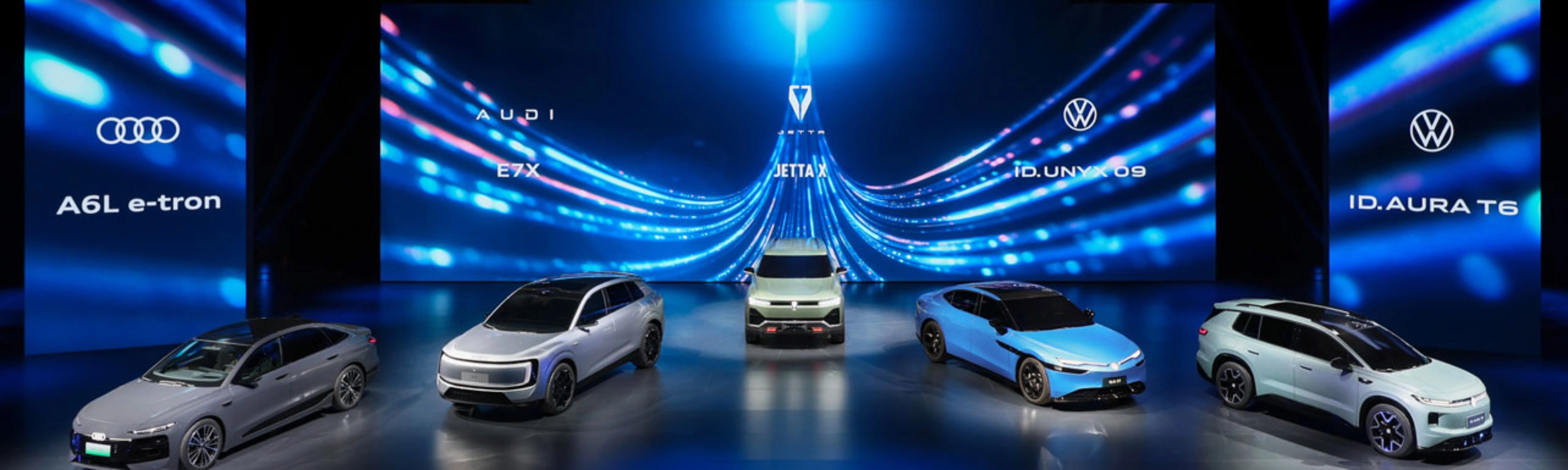 Five cars displayed on a stage with blue digital background.