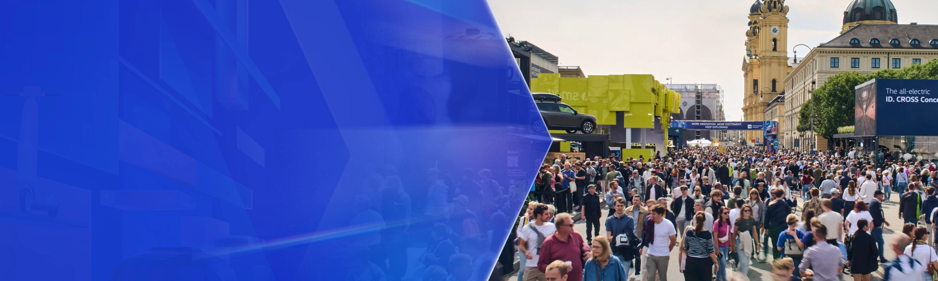 Große Menschenmenge auf einer Mobilitätsmesse im Freien mit Ausstellungsständen und Altbauten.