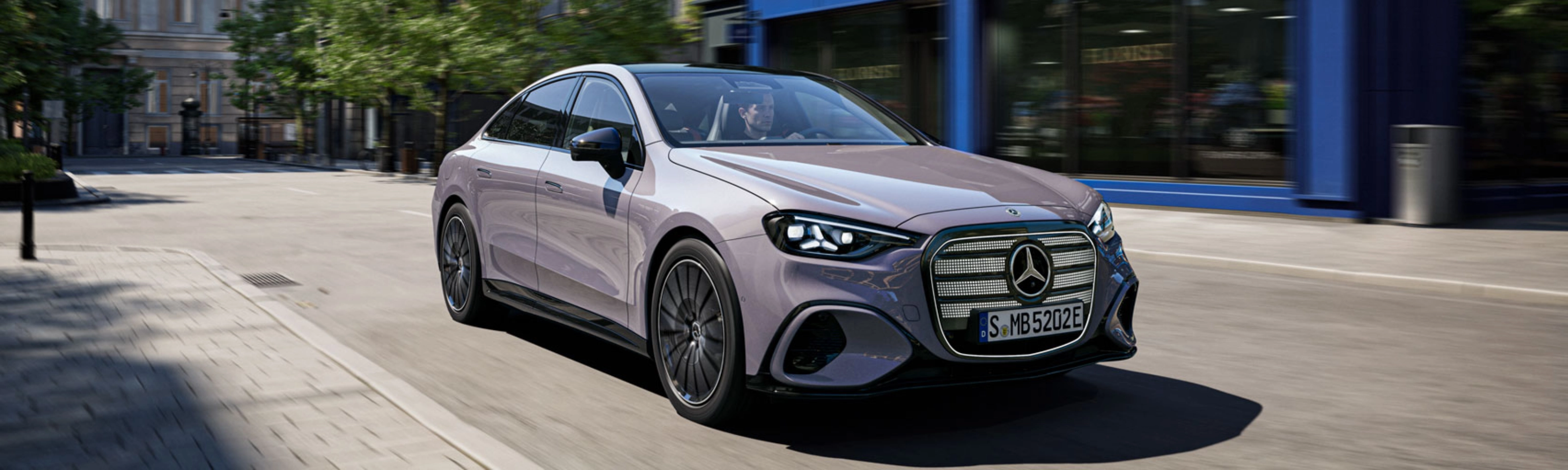 Graue Mercedes-Benz Limousine fährt durch eine Stadtstraße.