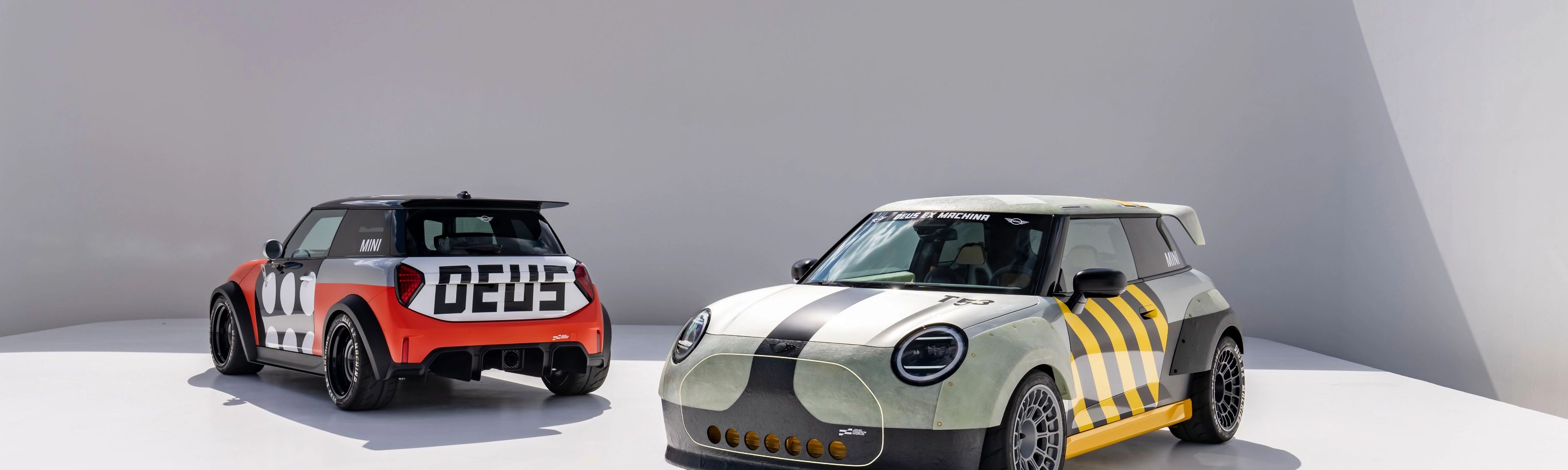 Two customized Mini cars parked in a minimalist outdoor setting.