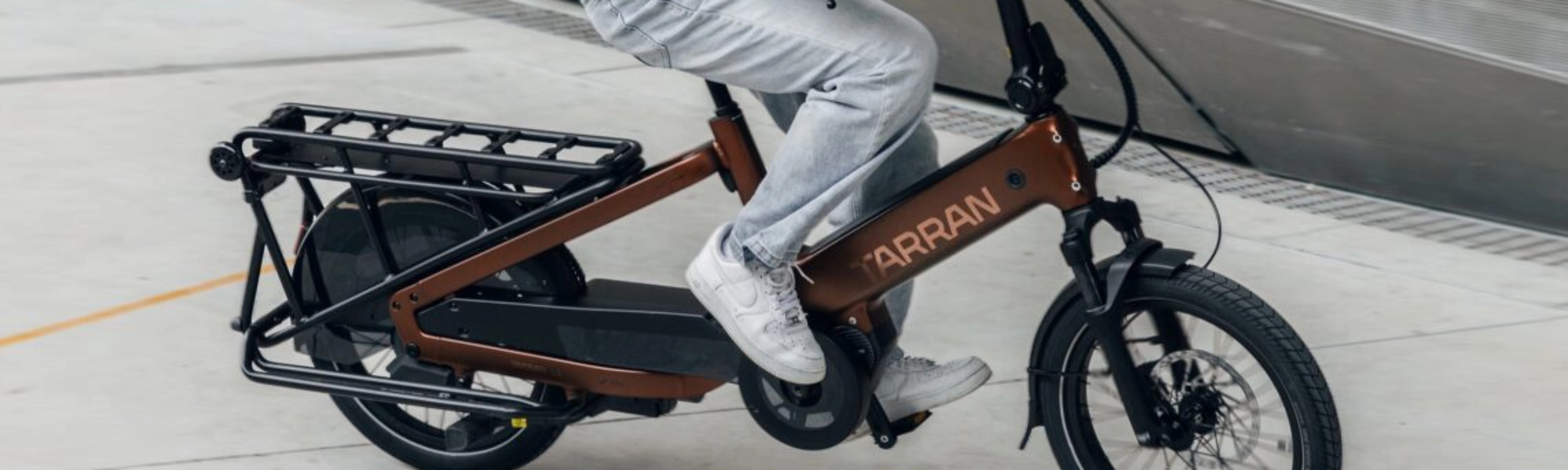 Person fährt ein Tarran Lasten-E-Bike in urbaner Umgebung.
