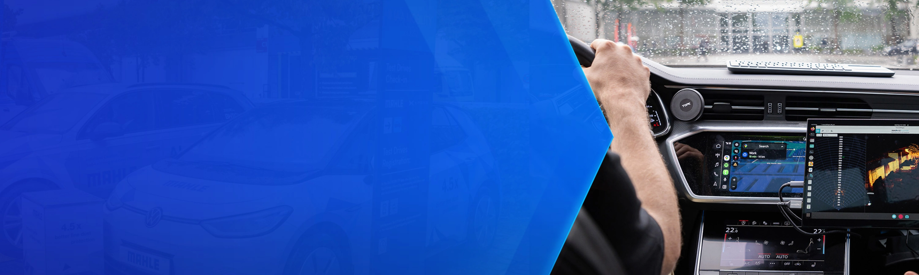 Driver tests in-car technology with navigation and monitoring screens during rainy conditions.
