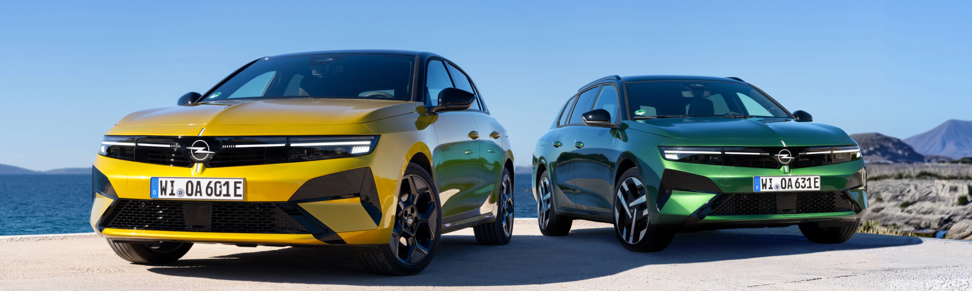 Gelber und grüner Opel stehen nebeneinander am Meer.