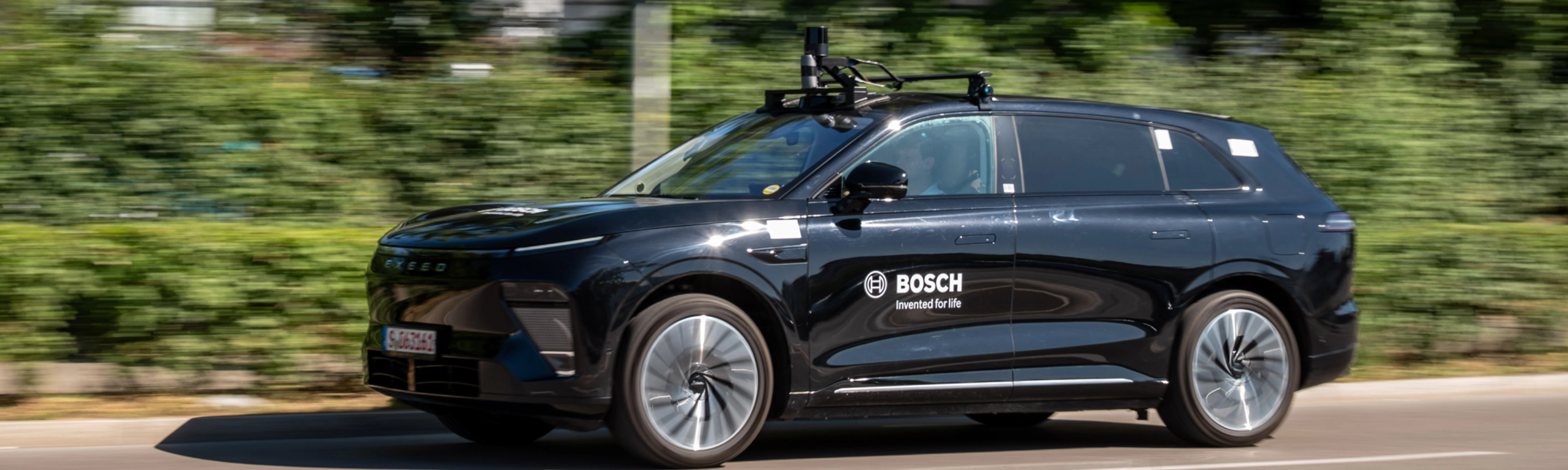 Schwarzer Bosch-Test-SUV mit Dachsensoren fährt auf Straße.