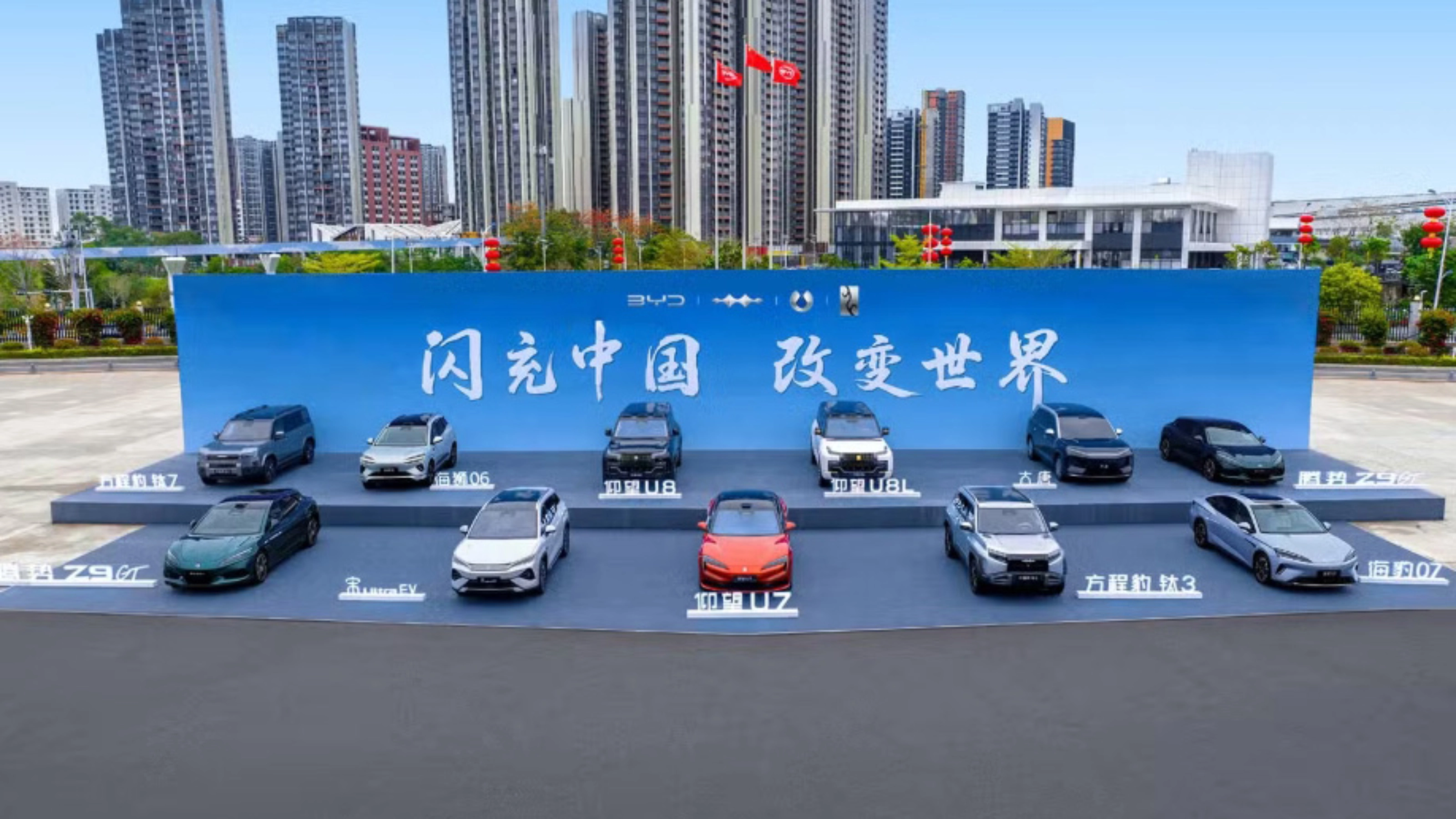 BYD vehicles displayed on a stage outdoors in front of a large promotional backdrop.