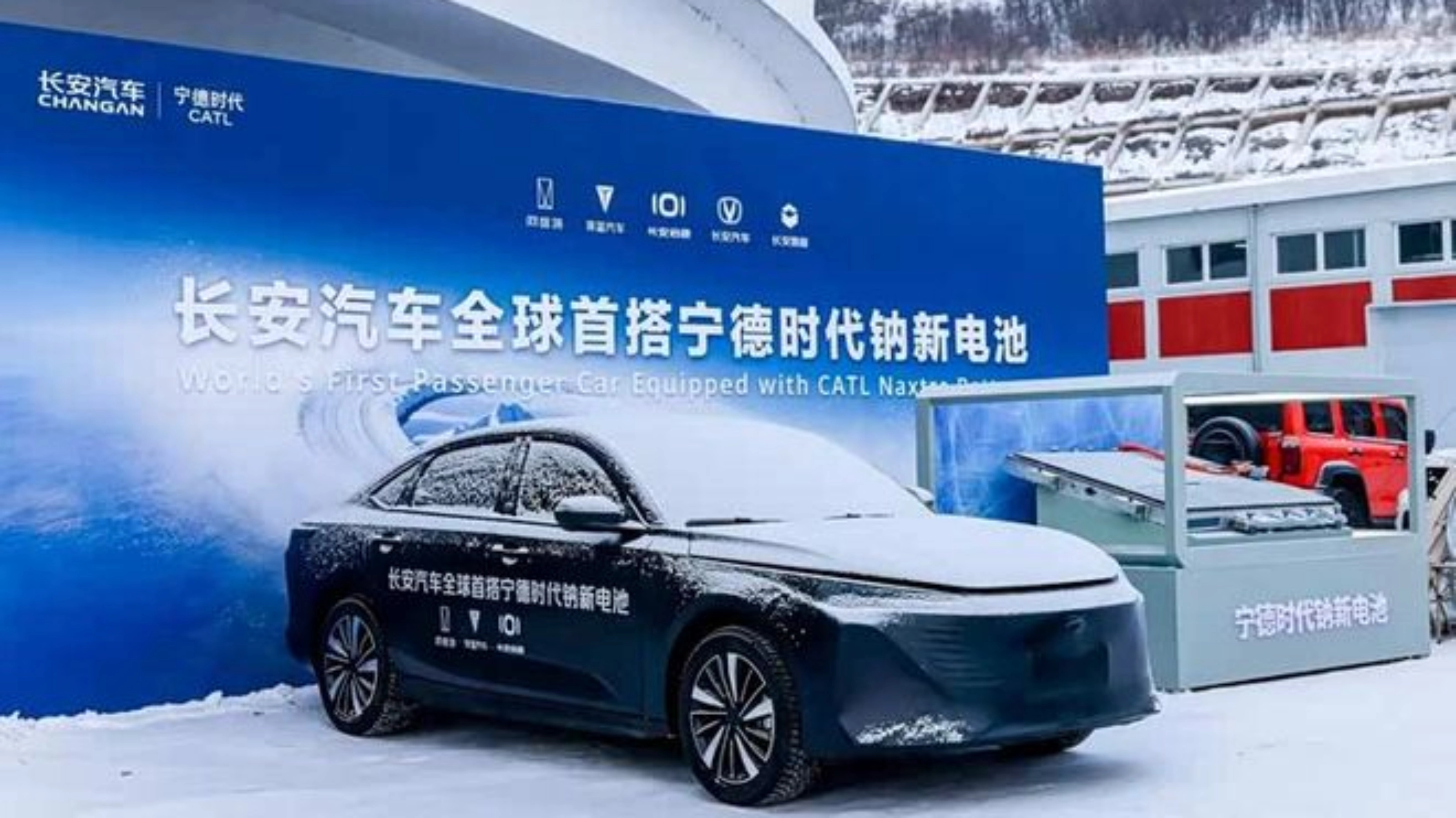 Elektroauto im Schnee vor Messestand mit chinesischem Banner.