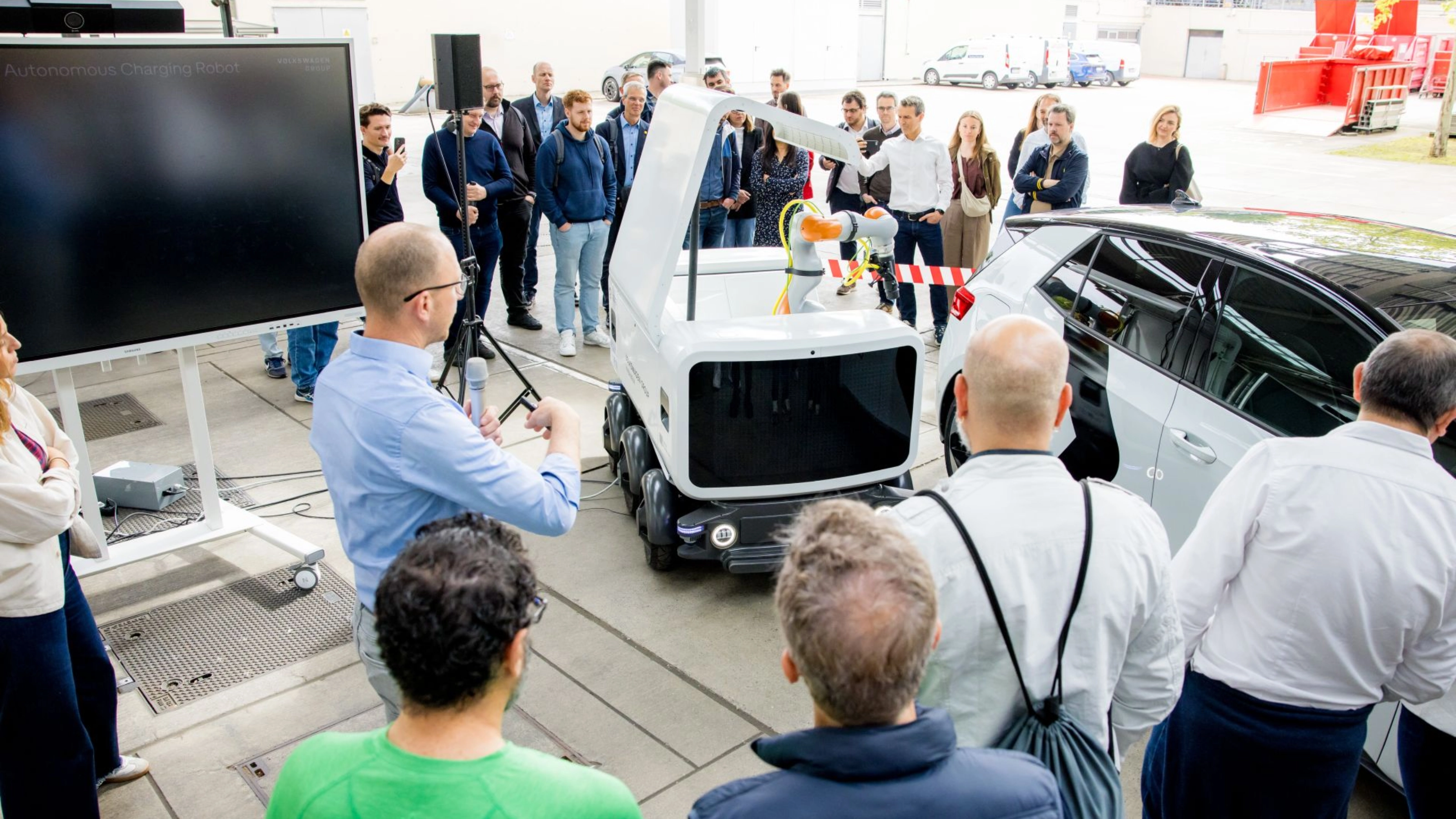 Group of people watching a Volkswagen vehicle demonstration at an outdoor event.