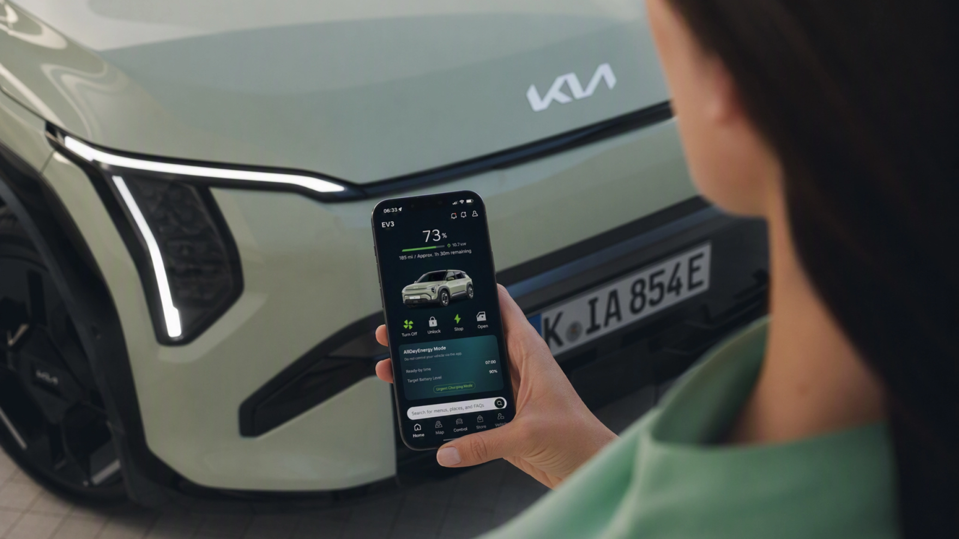Person nutzt ein Smartphone vor einem Kia-Elektroauto