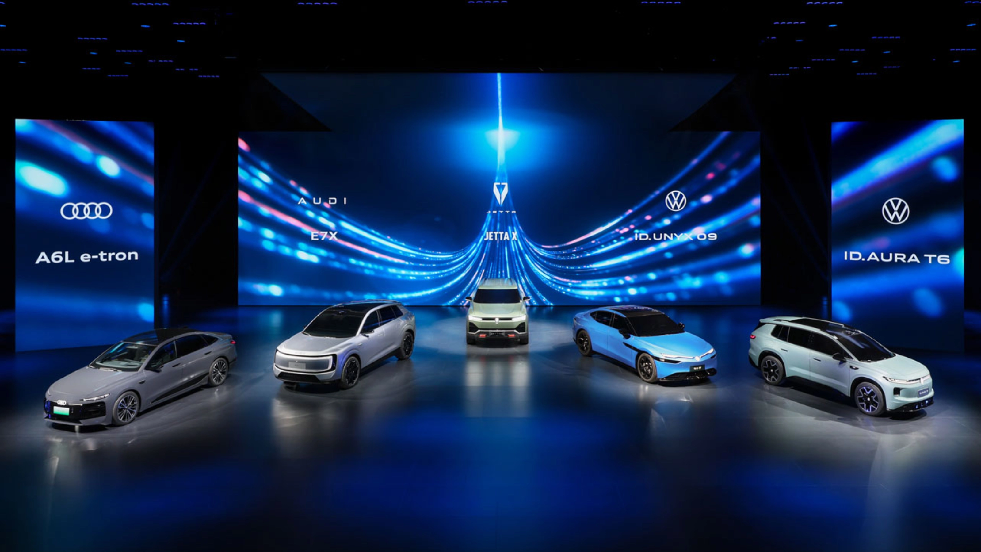 Five cars displayed on a stage with blue digital background.