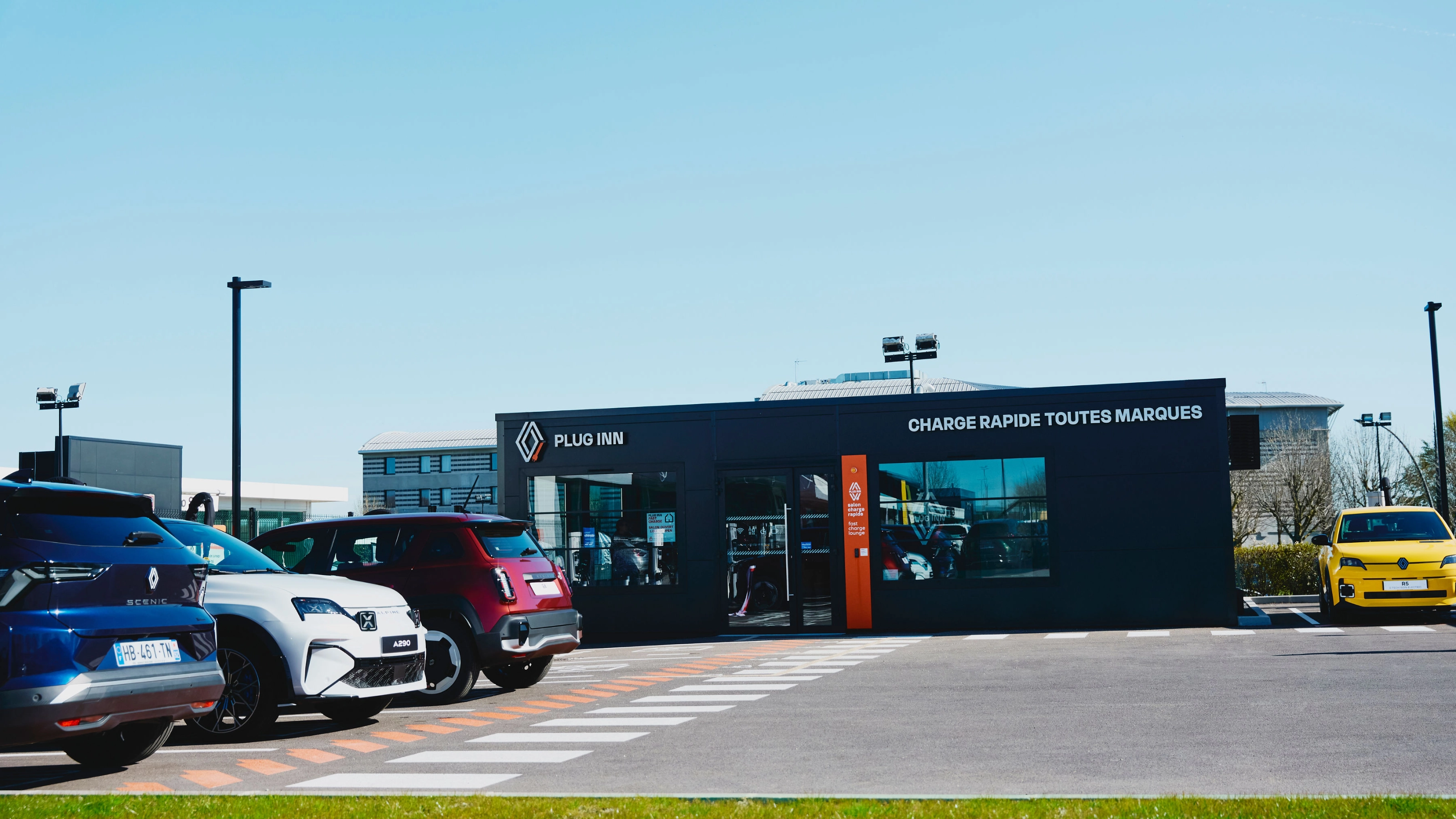 Außenansicht einer Plug-Inn-Schnellladestation mit mehreren geparkten Autos.