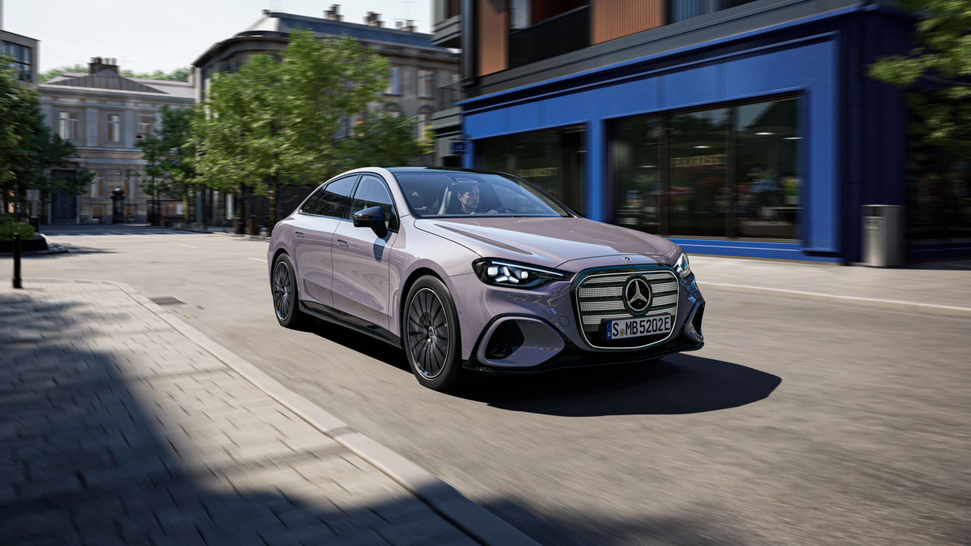Graue Mercedes-Benz Limousine fährt durch eine Stadtstraße.