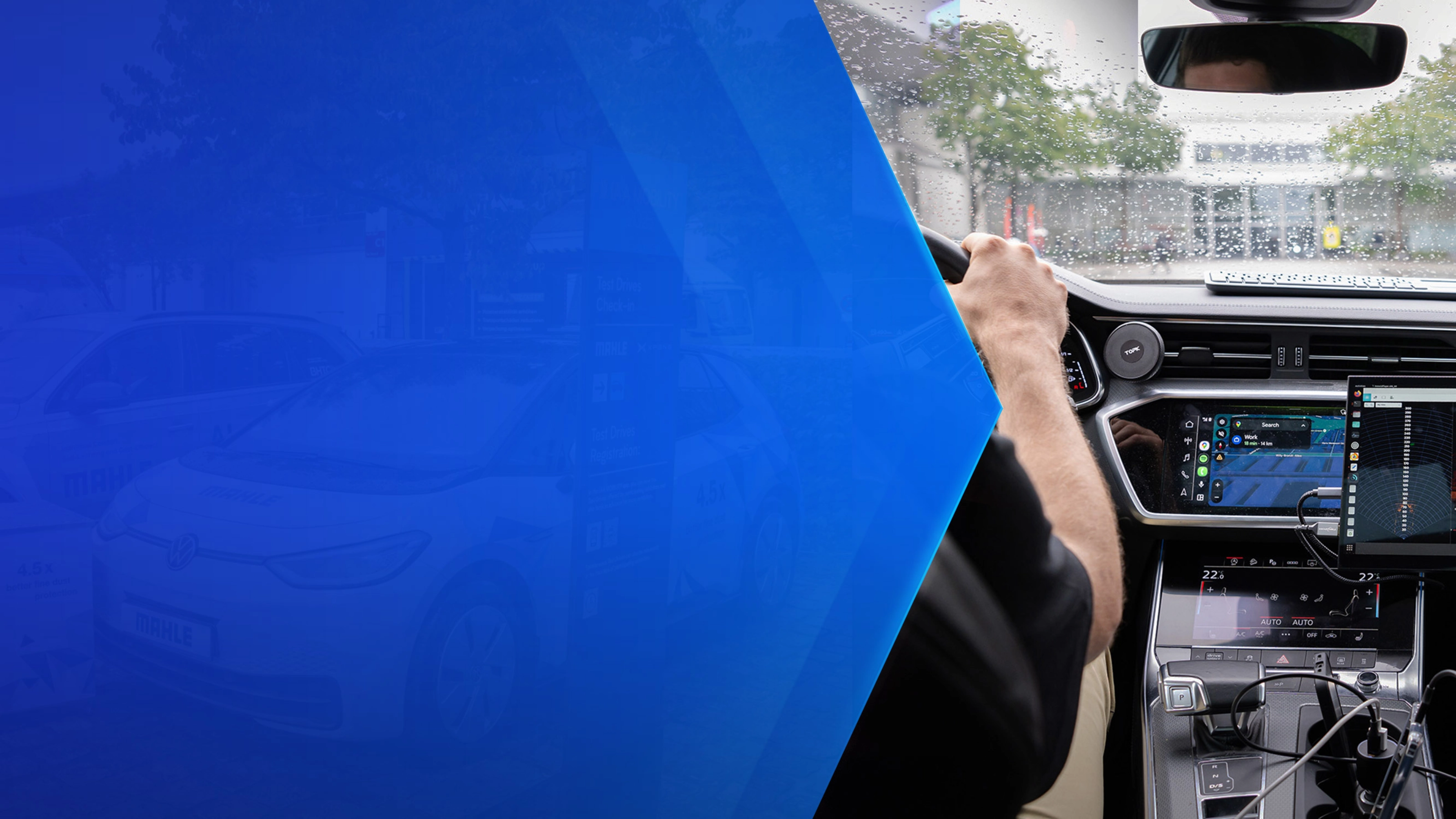 Driver tests in-car technology with navigation and monitoring screens during rainy conditions.