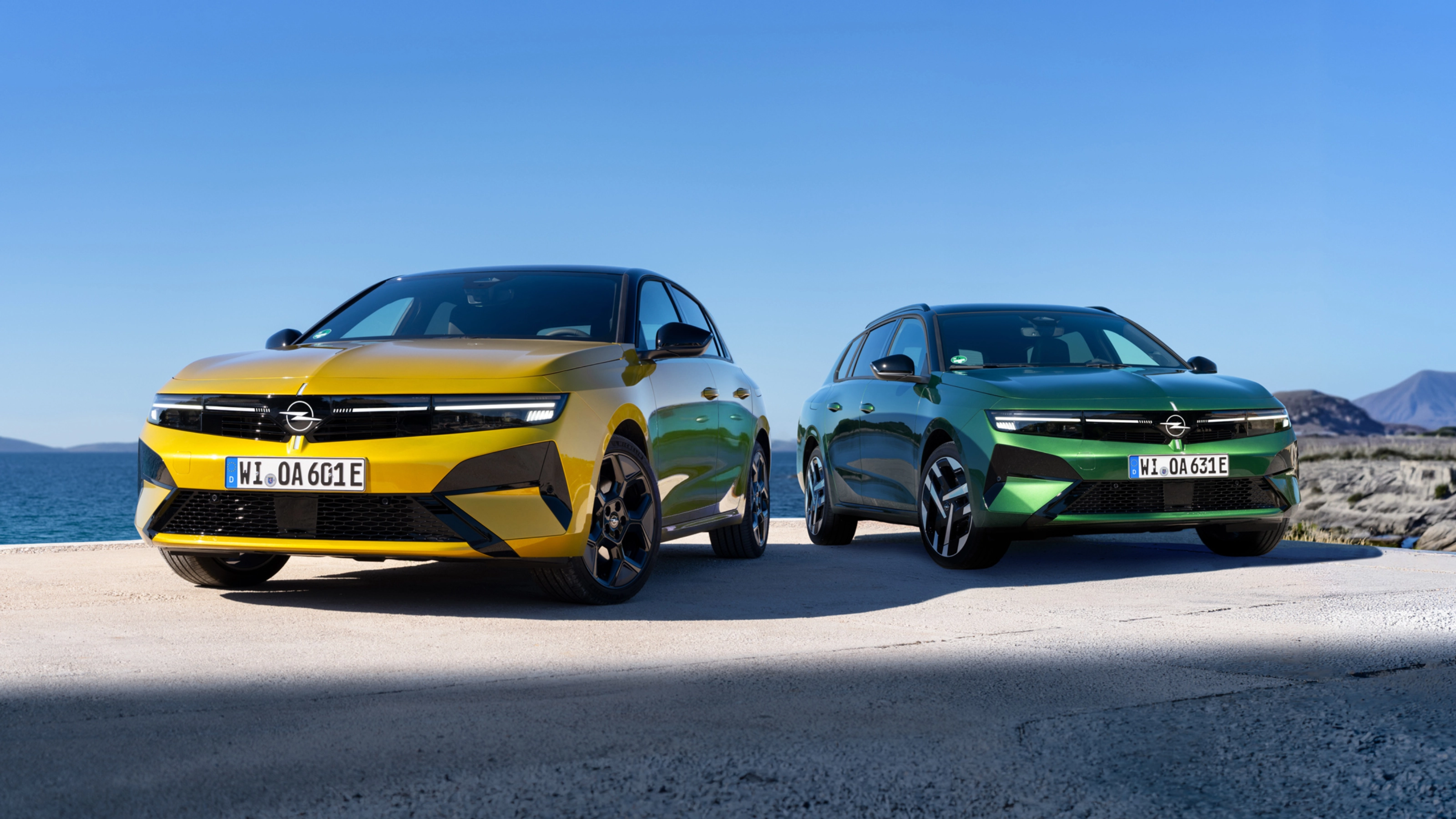 Gelber und grüner Opel stehen nebeneinander am Meer.