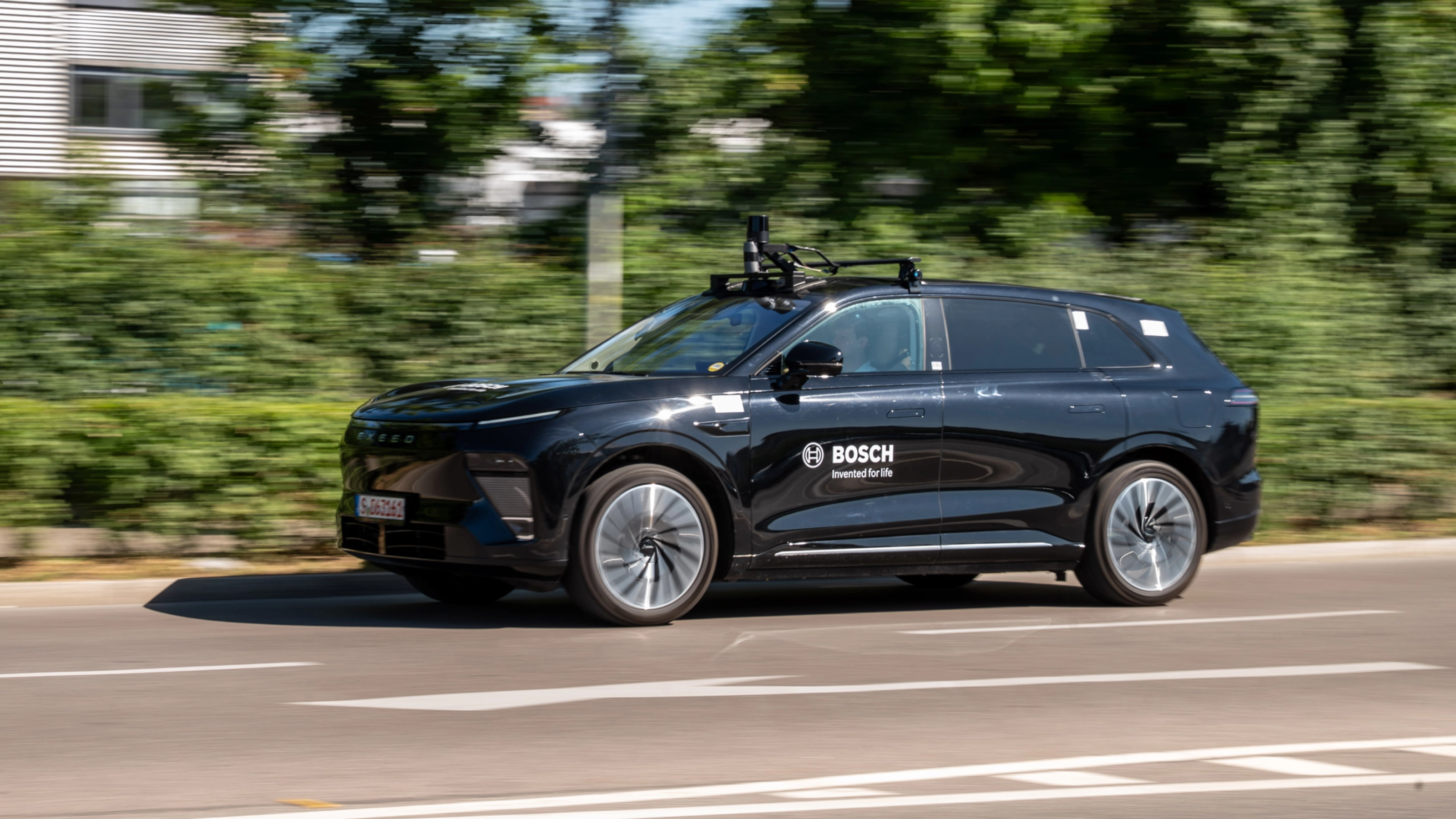Schwarzer Bosch-Test-SUV mit Dachsensoren fährt auf Straße.