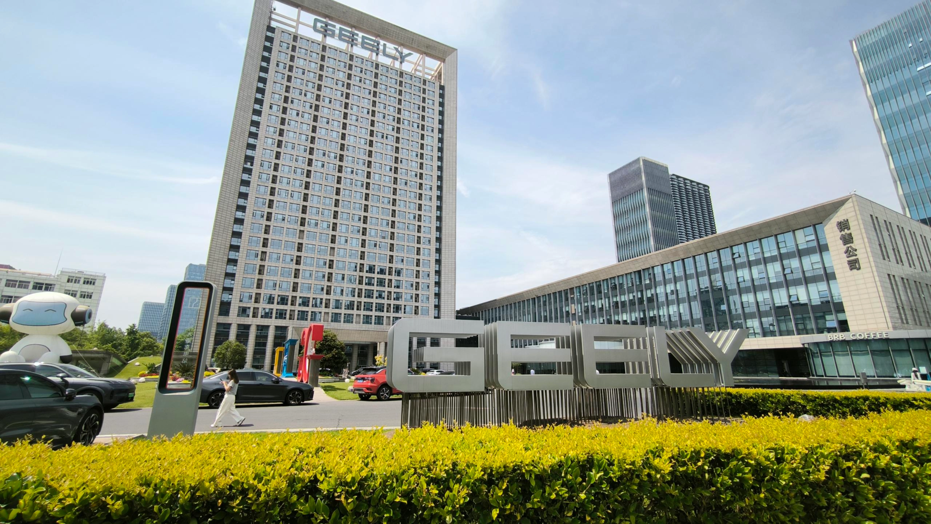 Geely-Logo vor einem modernen Bürogebäude.