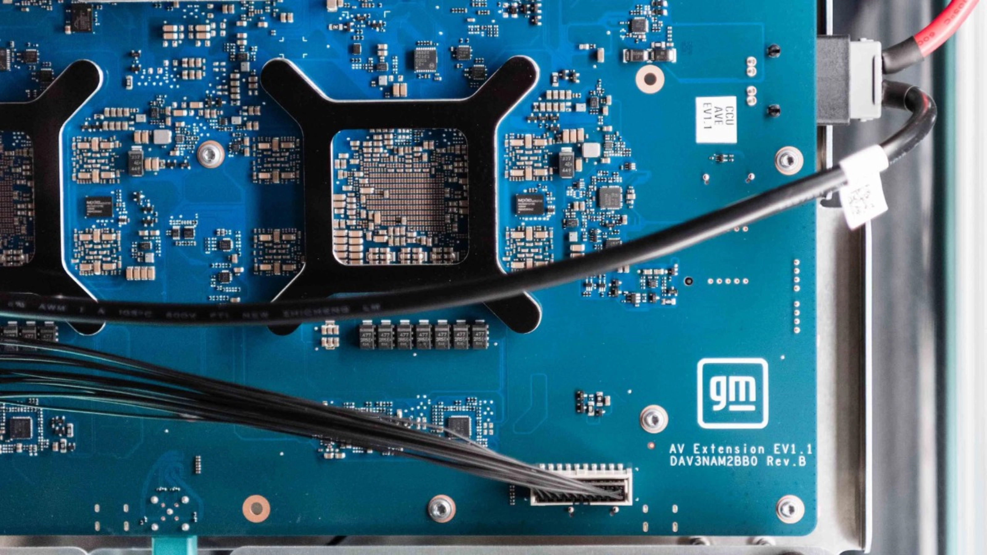 Close-up of a blue General Motors circuit board with electronic components and connectors.