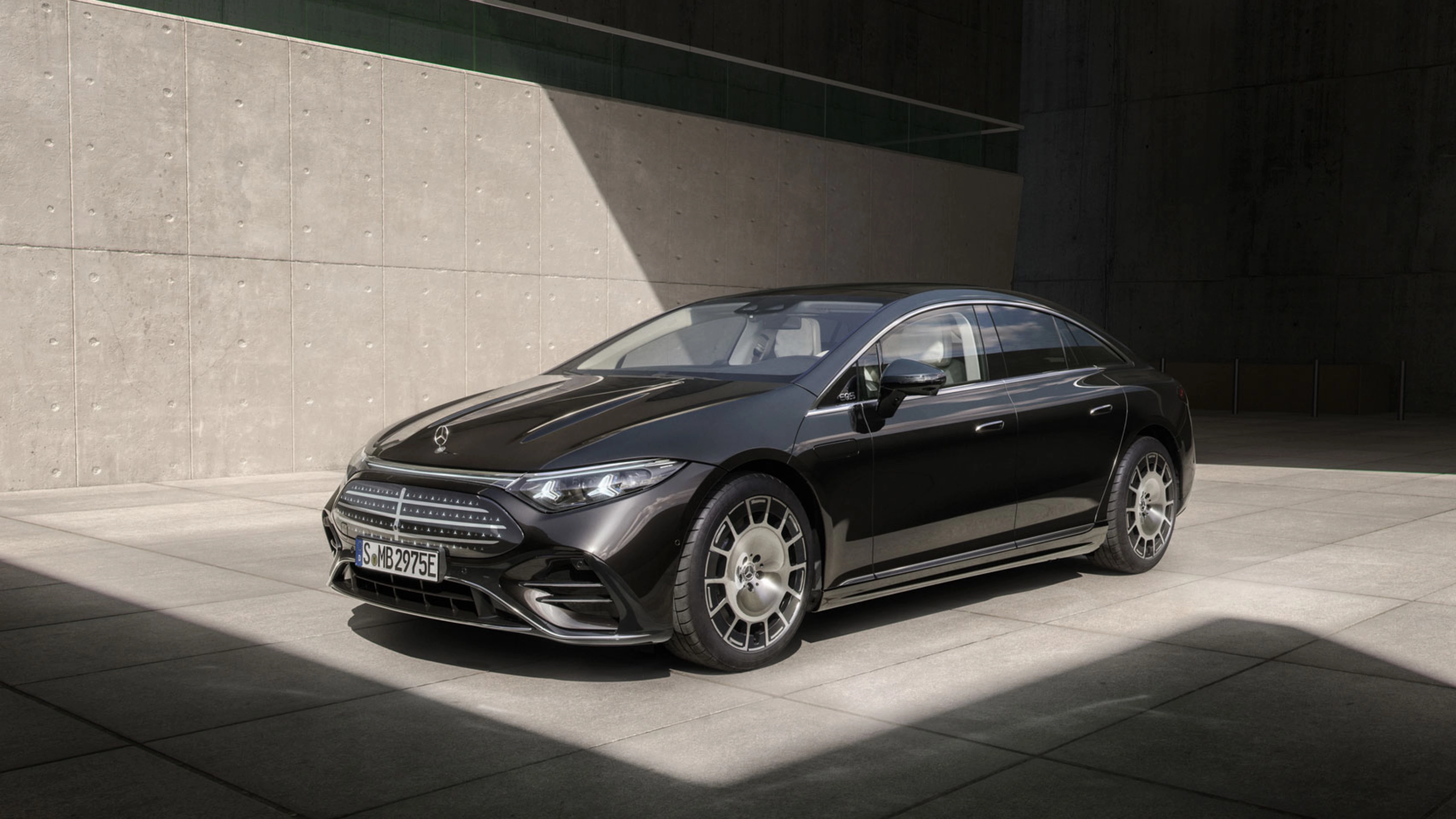 Schwarzer Mercedes-Benz steht im Sonnenlicht vor einer Betonwand
