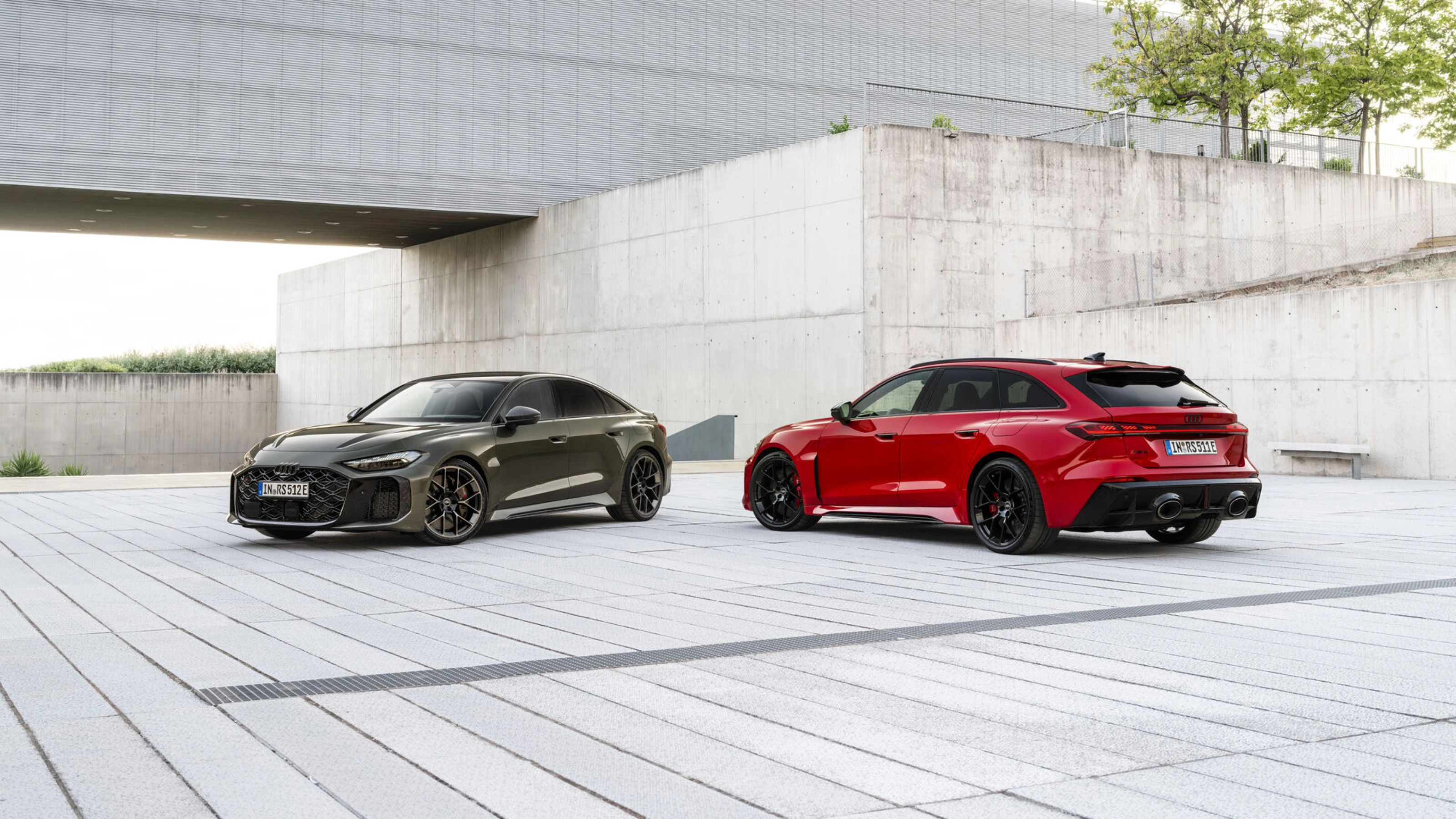 Two Audi performance cars parked in a modern concrete courtyard.