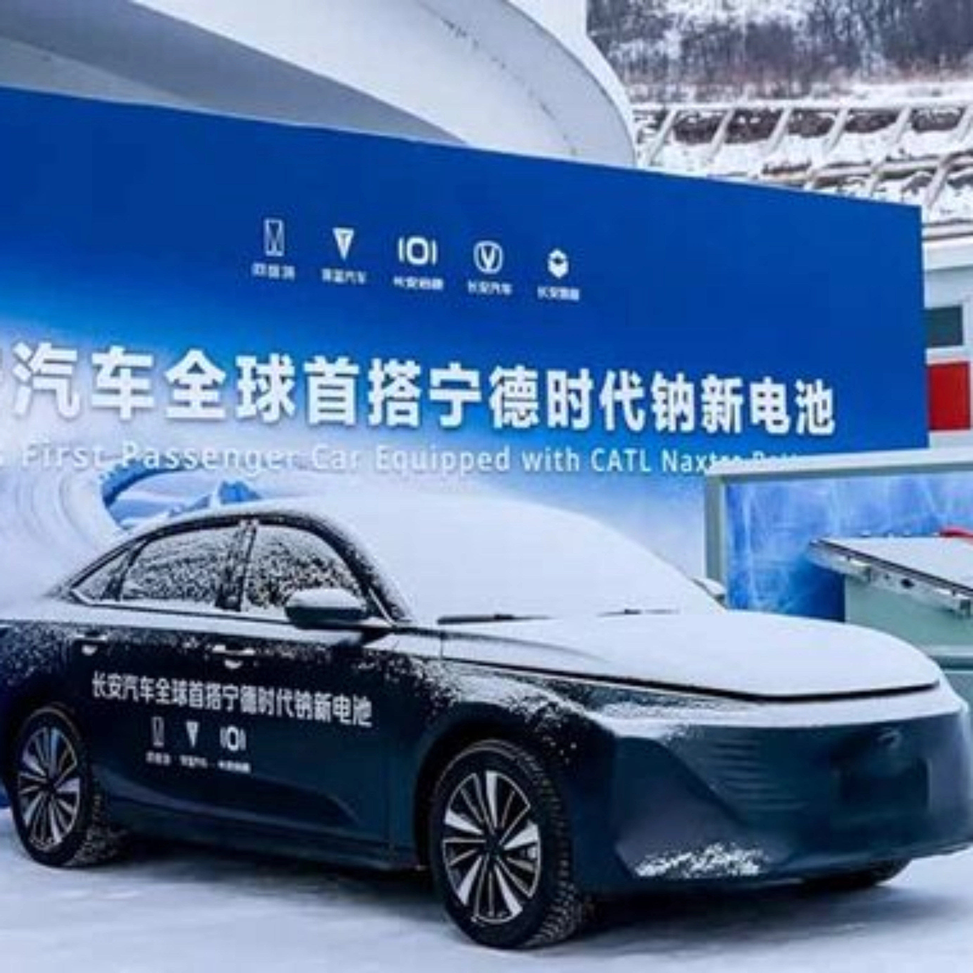 Elektroauto im Schnee vor Messestand mit chinesischem Banner.
