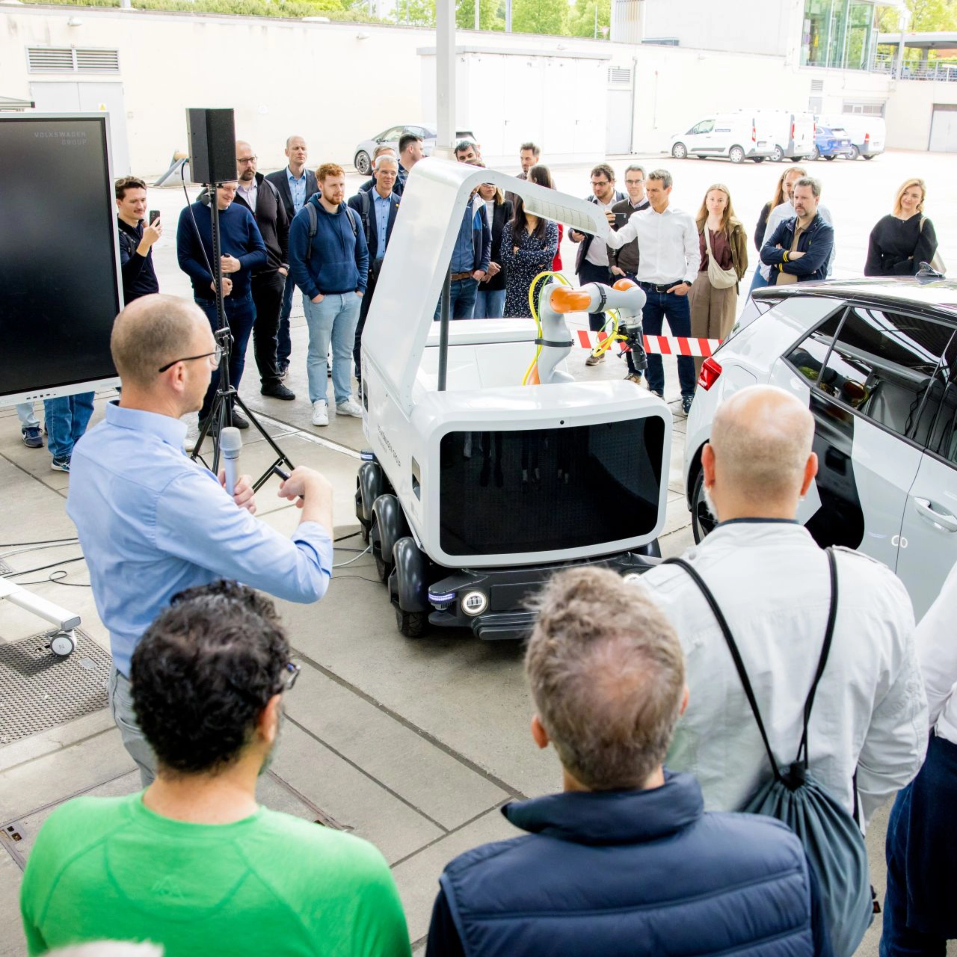 Group of people watching a Volkswagen vehicle demonstration at an outdoor event.