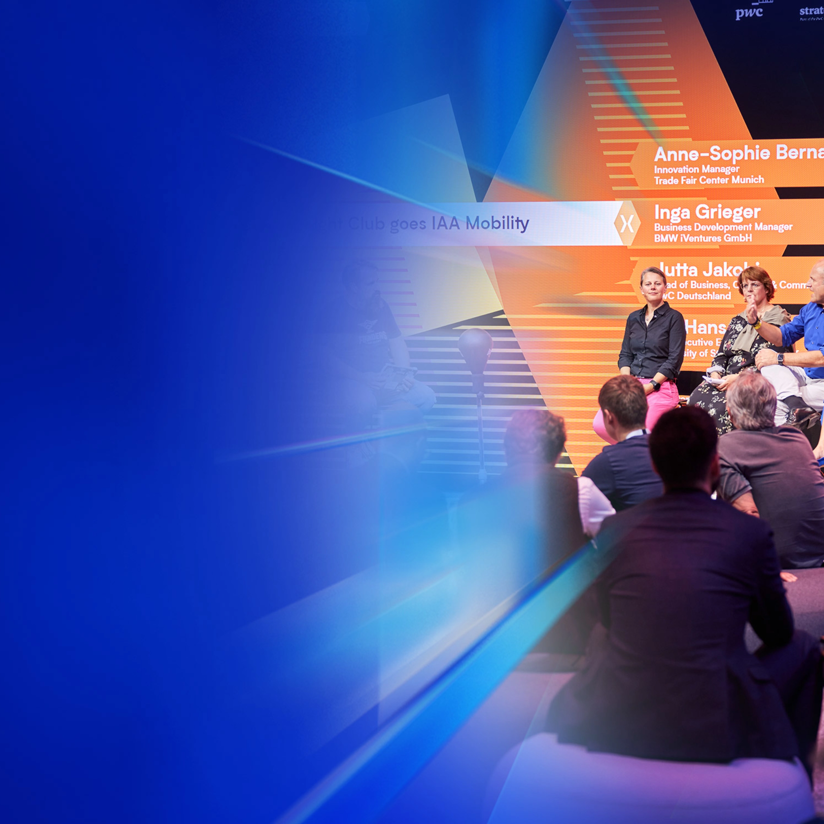 Ein Panel mit fünf Personen spricht auf der Bühne des IAA Summit, das Publikum hört zu.