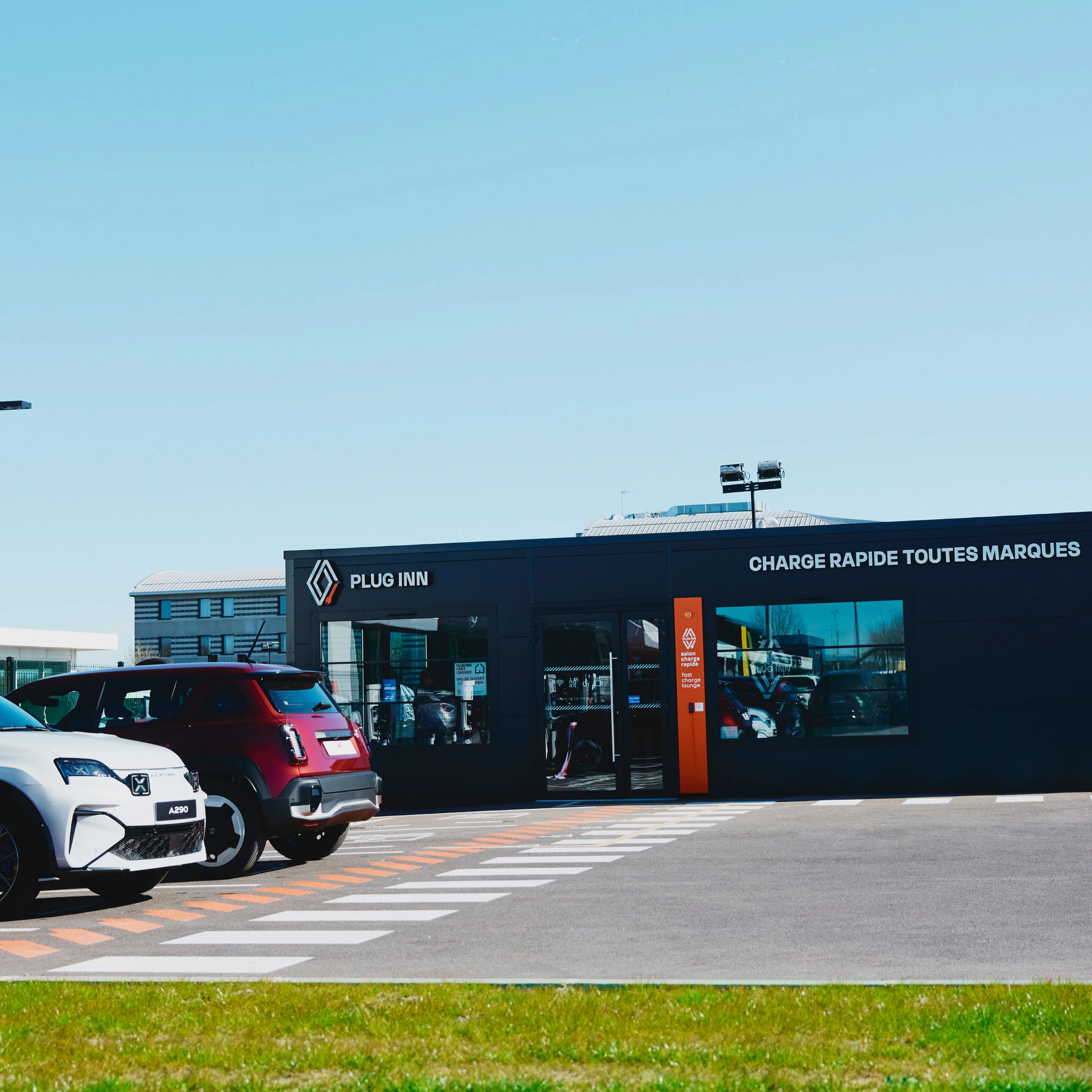 Außenansicht einer Plug-Inn-Schnellladestation mit mehreren geparkten Autos.