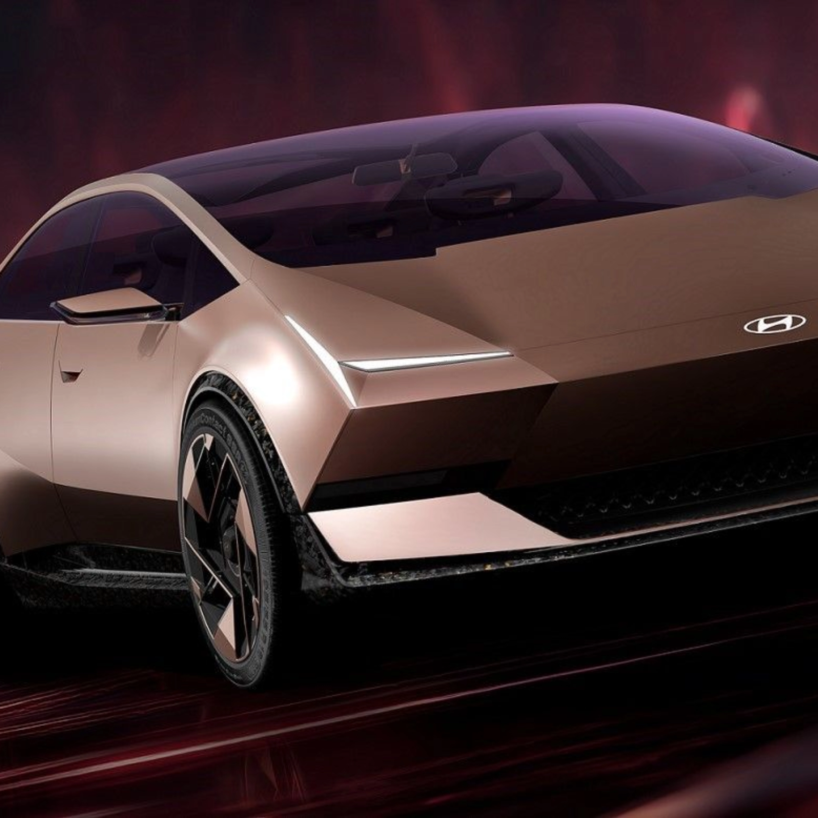 Futuristic Hyundai electric car driving in a red illuminated studio setting.
