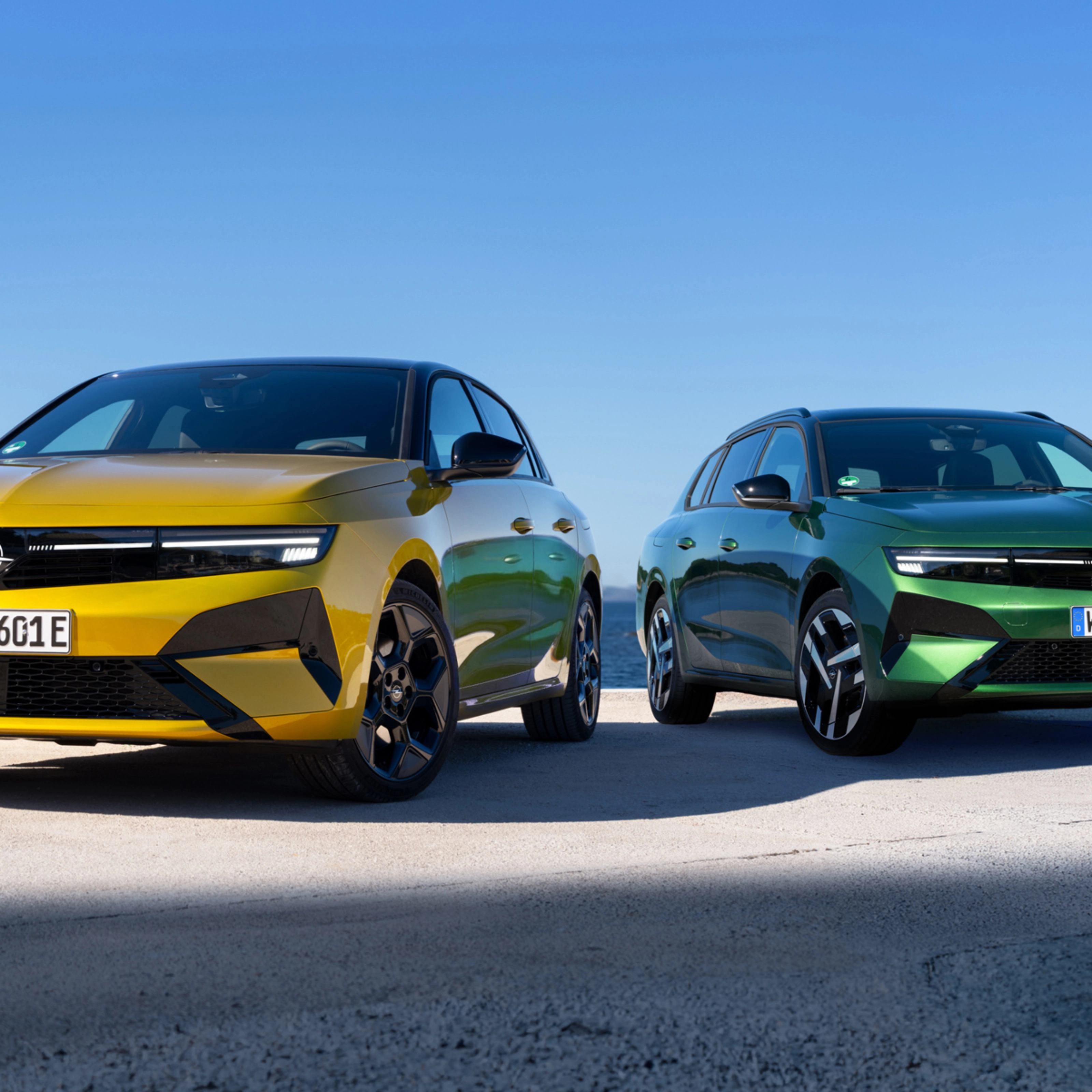Gelber und grüner Opel stehen nebeneinander am Meer.