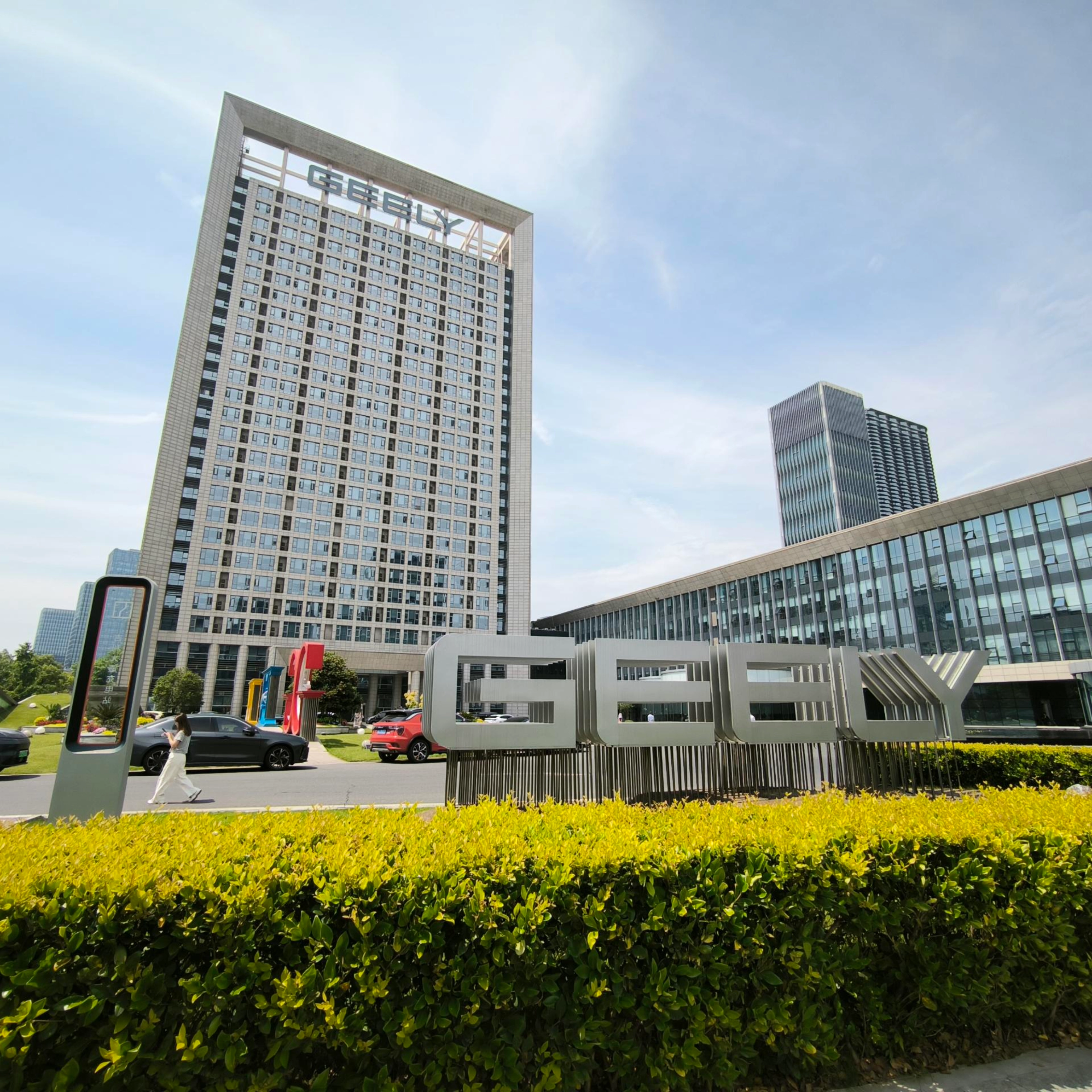 Geely-Logo vor einem modernen Bürogebäude.