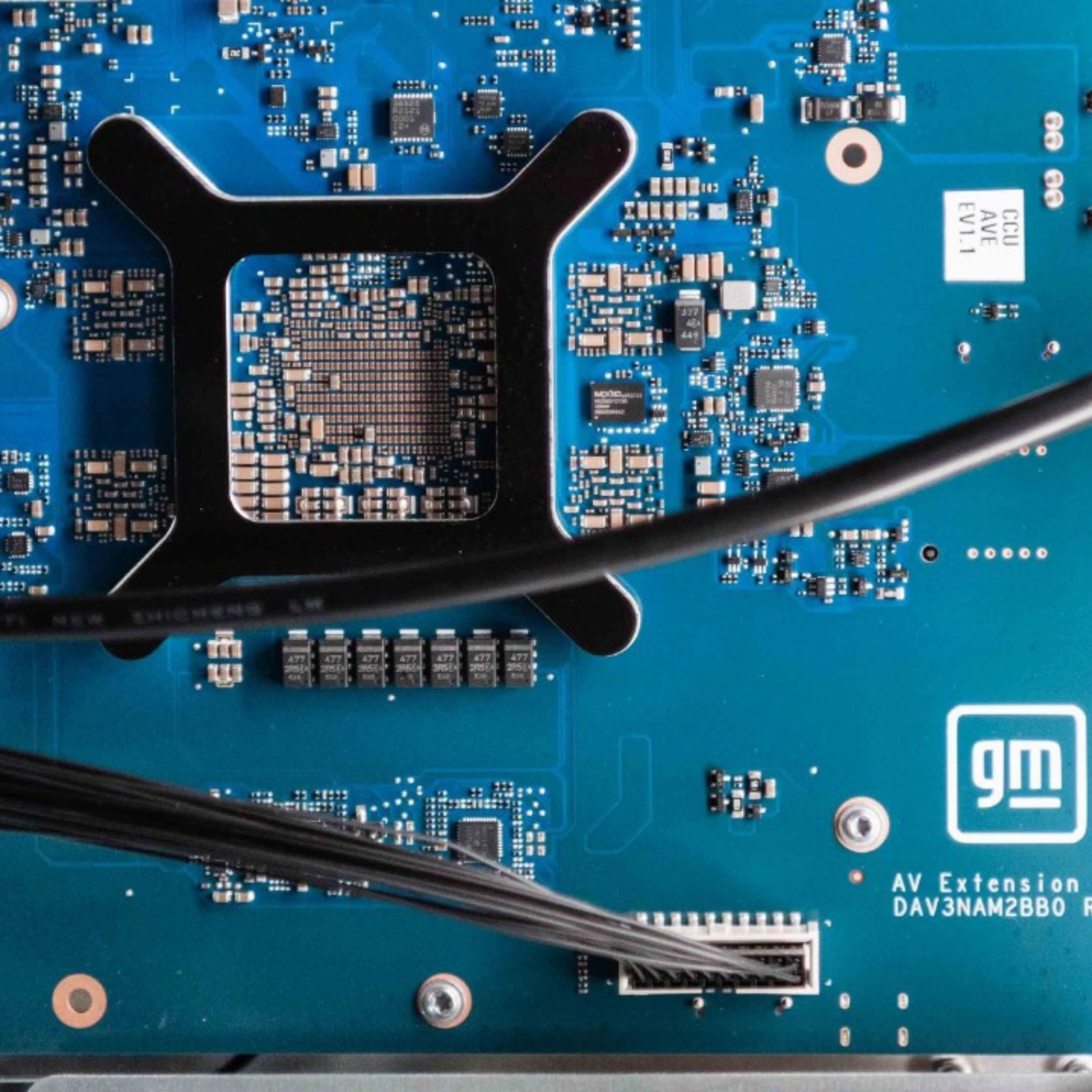 Close-up of a blue General Motors circuit board with electronic components and connectors.