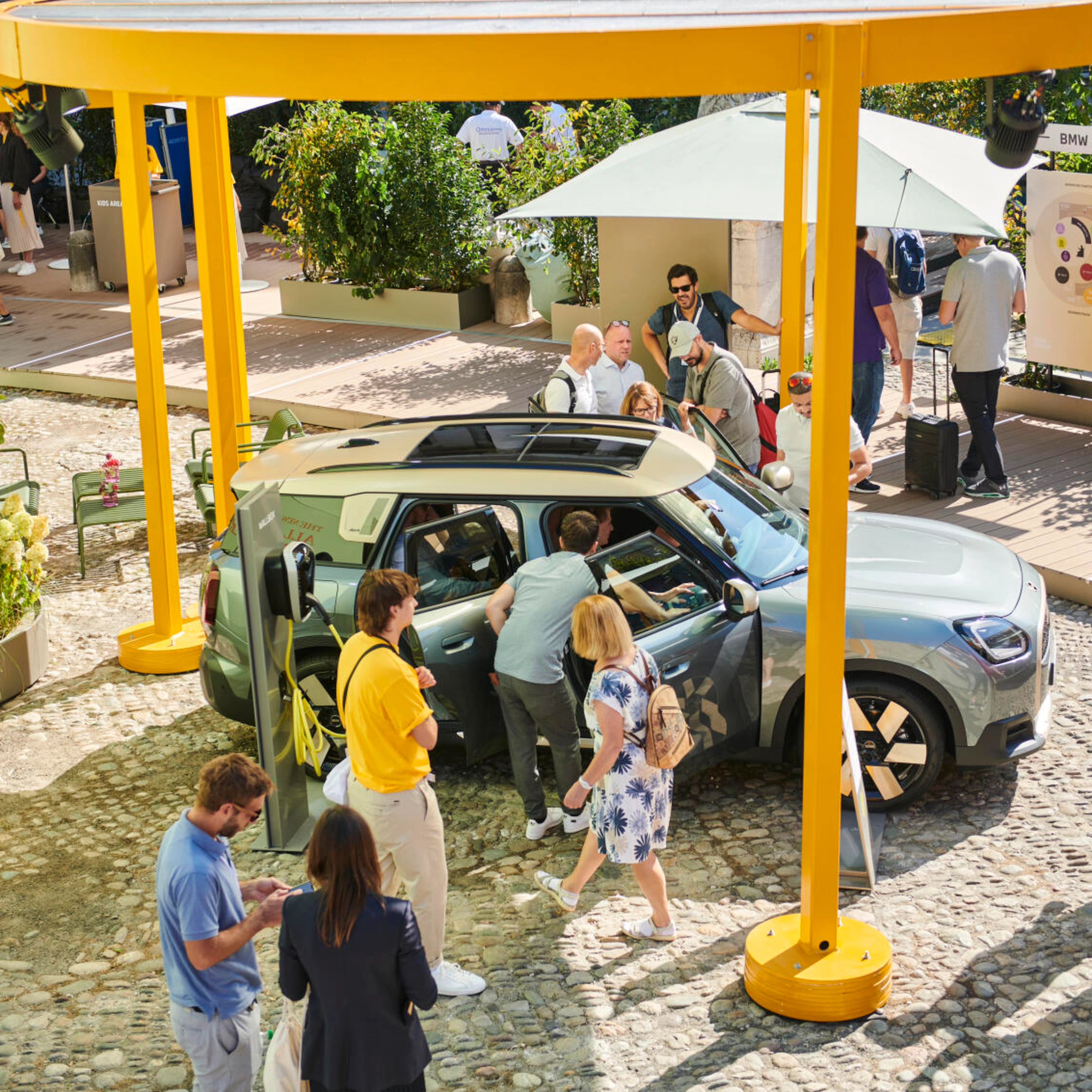 People at an outdoor event looking at a concept car on display.