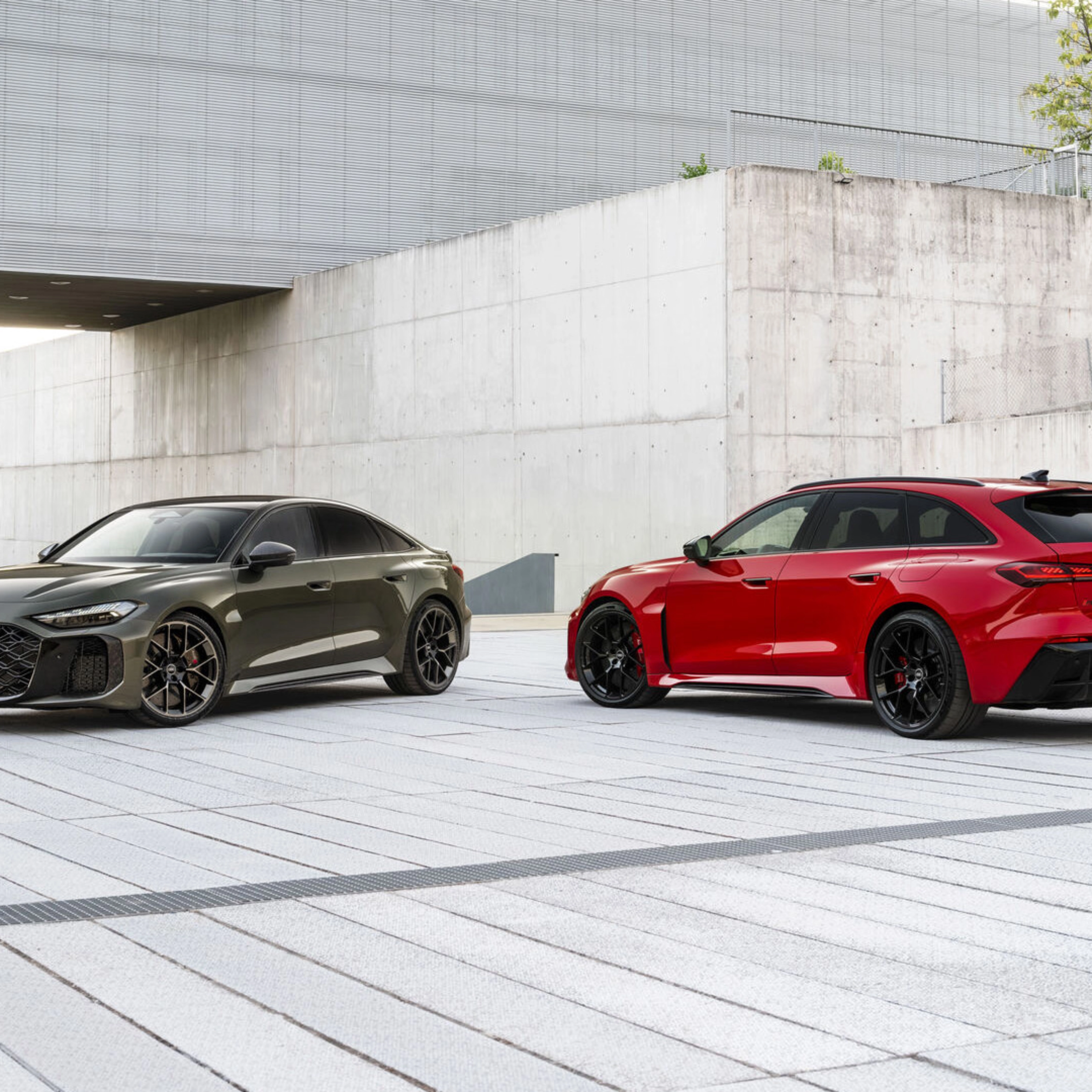 Two Audi performance cars parked in a modern concrete courtyard.