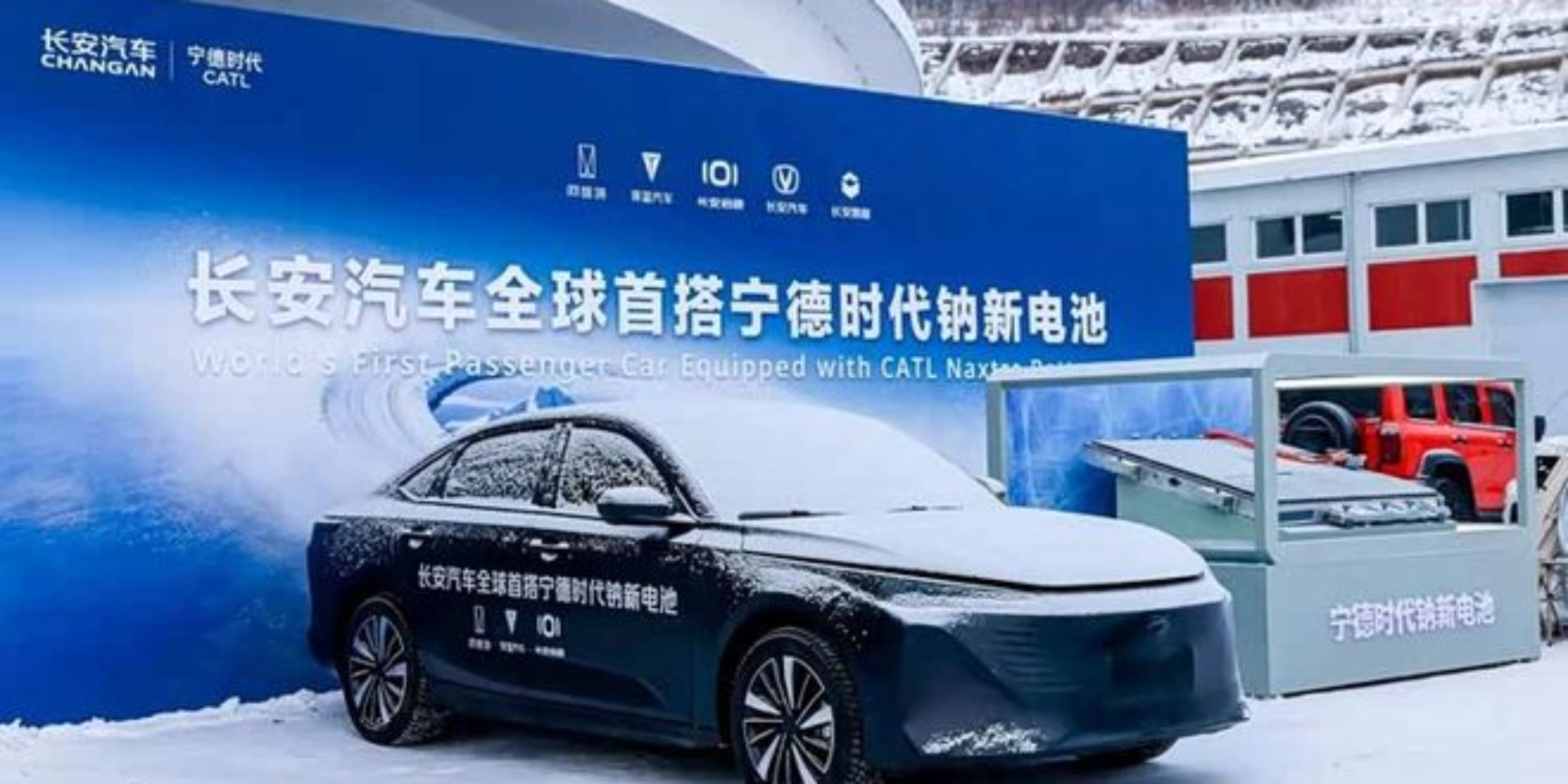 Elektroauto im Schnee vor Messestand mit chinesischem Banner.
