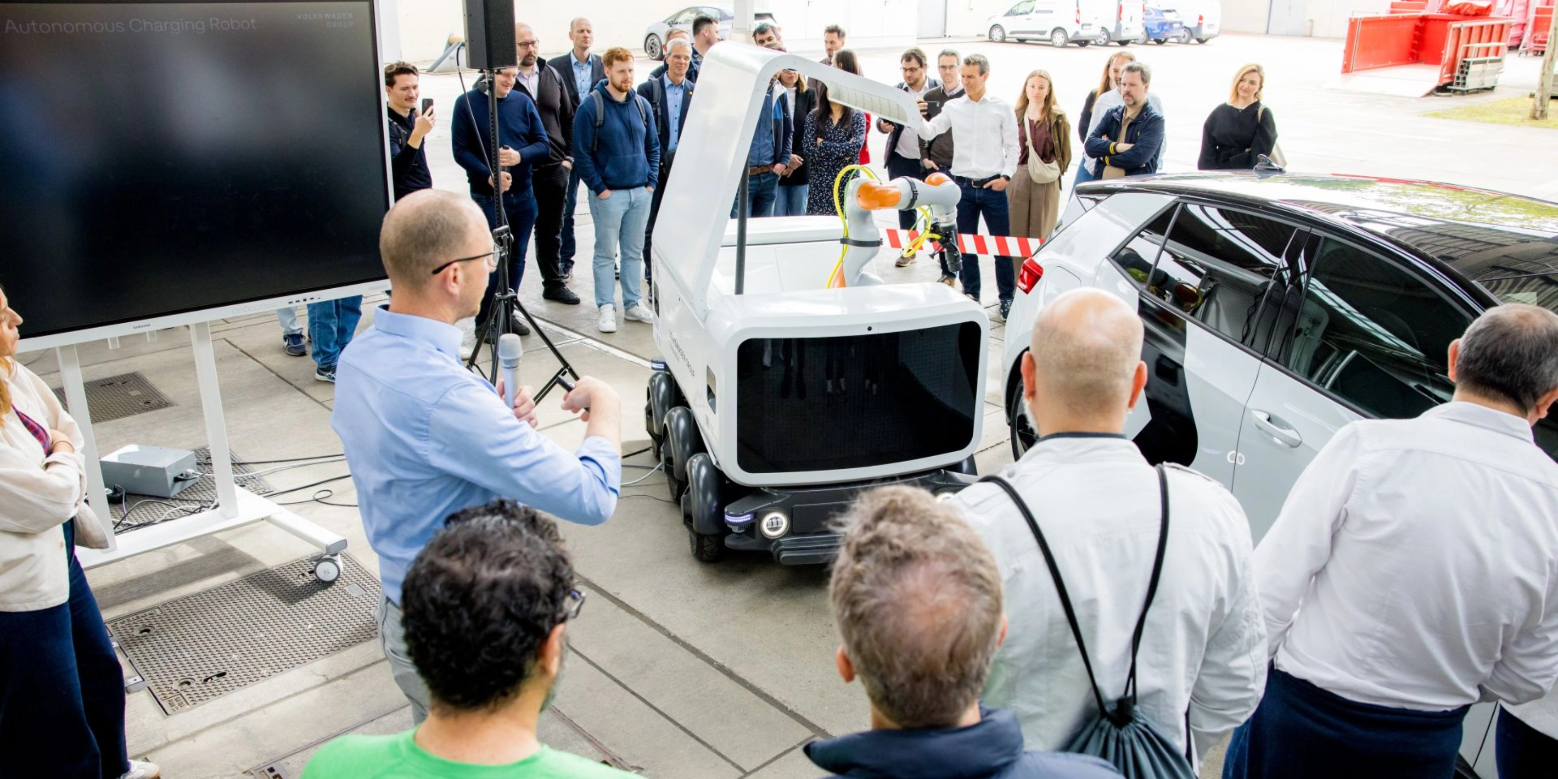 Group of people watching a Volkswagen vehicle demonstration at an outdoor event.