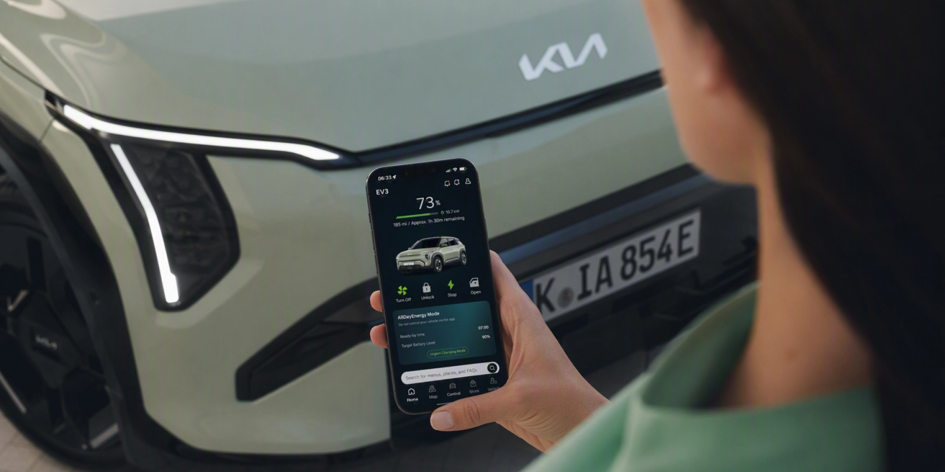 Person nutzt ein Smartphone vor einem Kia-Elektroauto