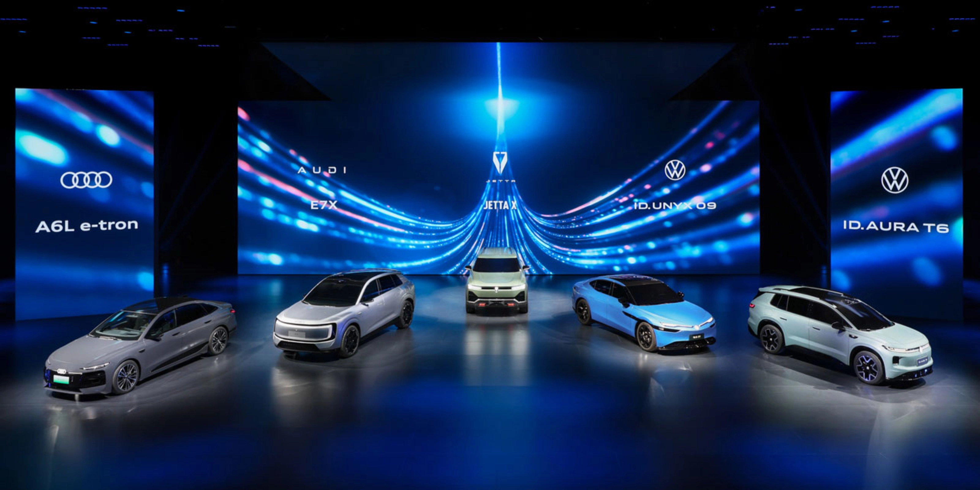 Five cars displayed on a stage with blue digital background.