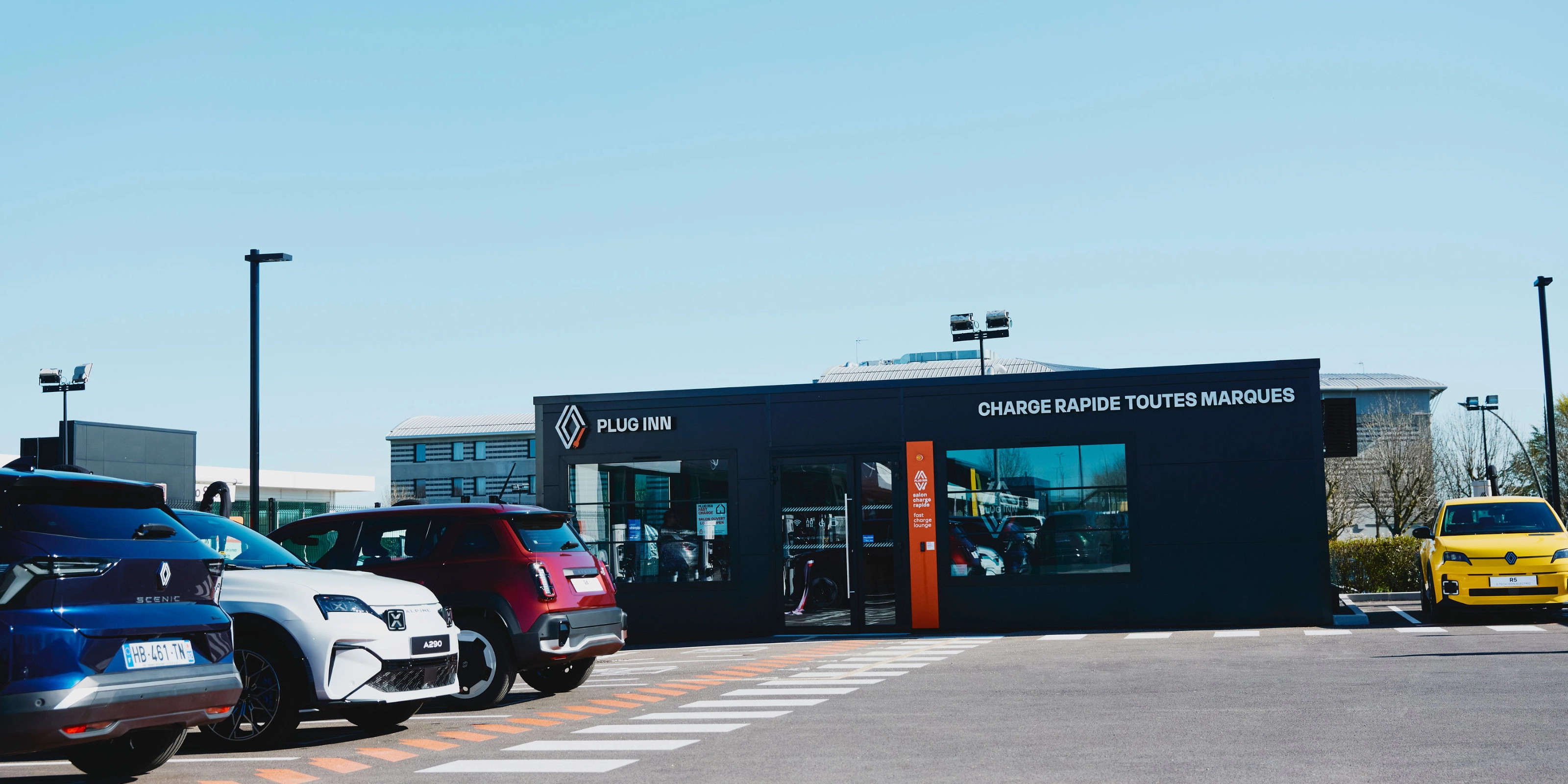 Außenansicht einer Plug-Inn-Schnellladestation mit mehreren geparkten Autos.