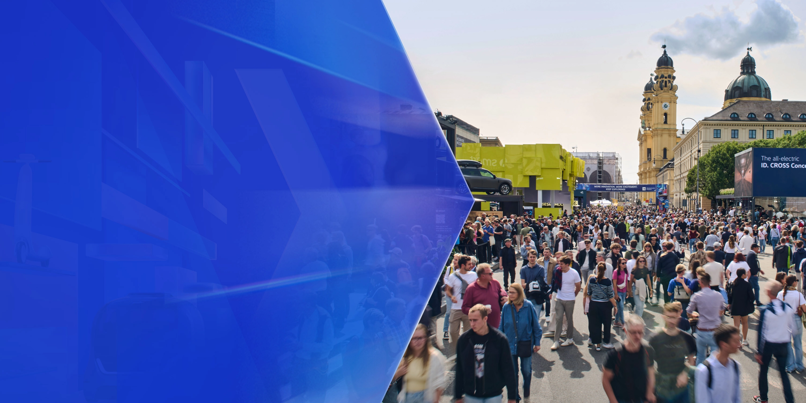 Große Menschenmenge auf einer Mobilitätsmesse im Freien mit Ausstellungsständen und Altbauten.