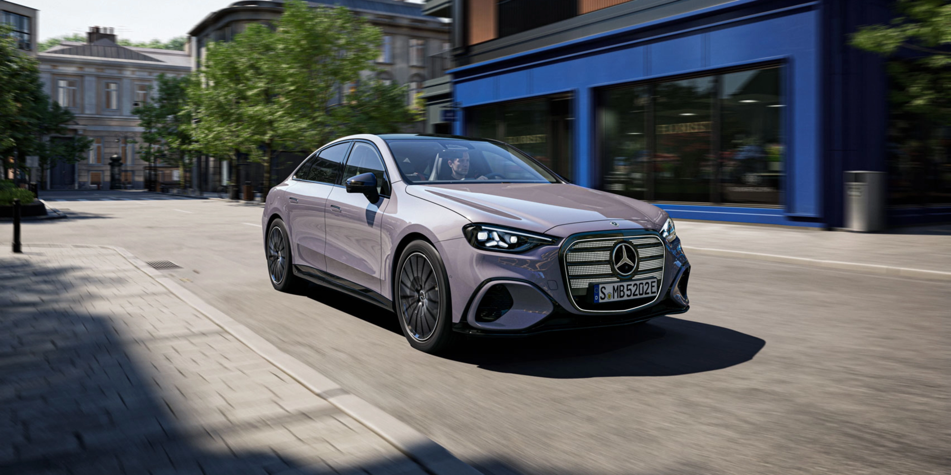 Graue Mercedes-Benz Limousine fährt durch eine Stadtstraße.