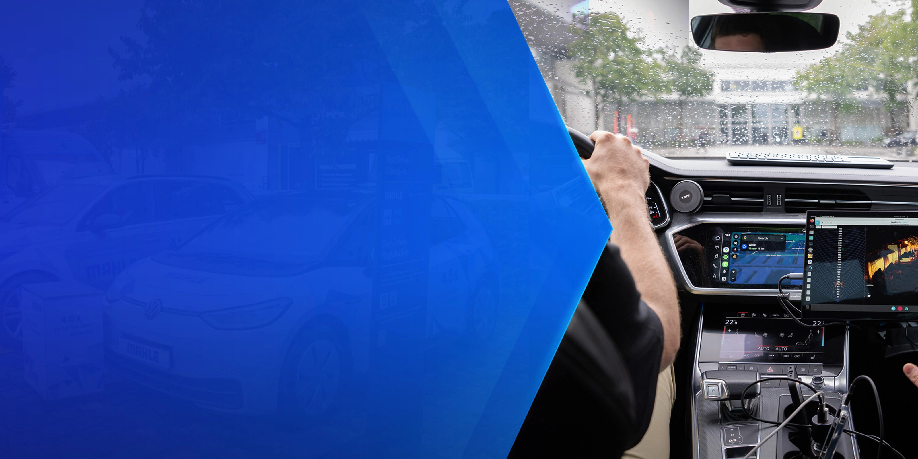 Driver tests in-car technology with navigation and monitoring screens during rainy conditions.
