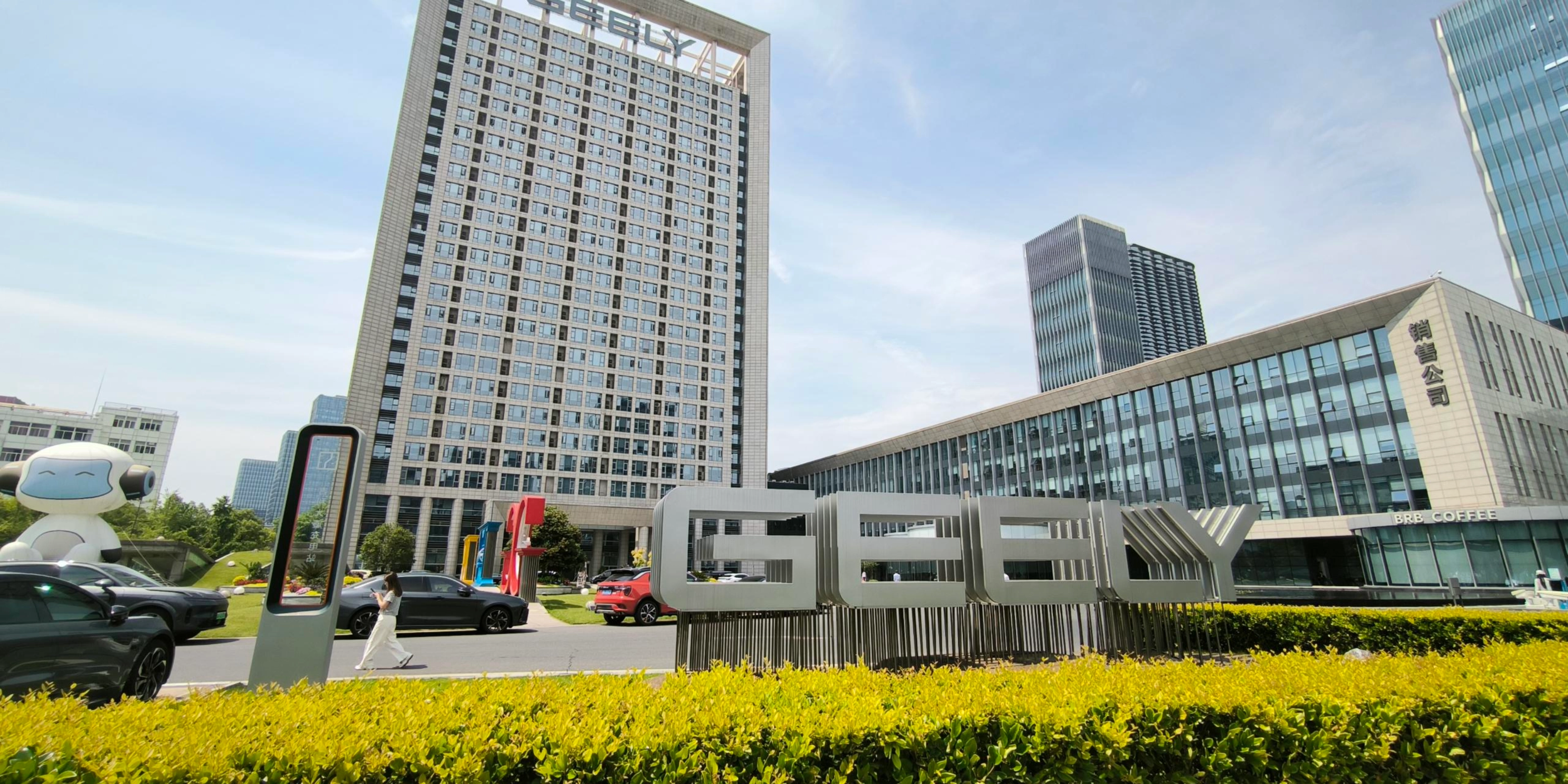 Geely-Logo vor einem modernen Bürogebäude.
