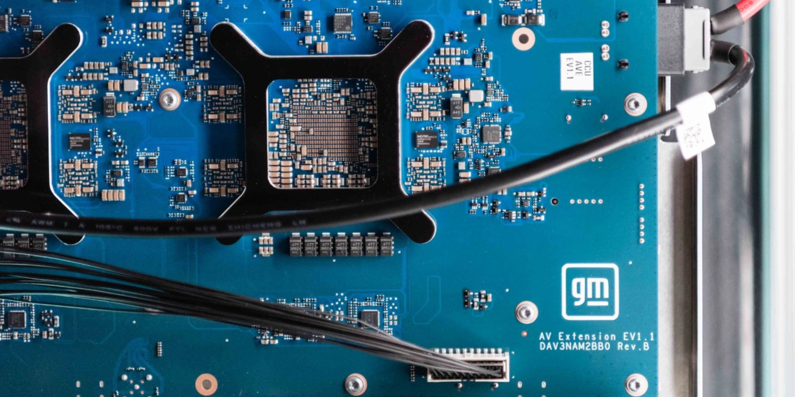 Close-up of a blue General Motors circuit board with electronic components and connectors.