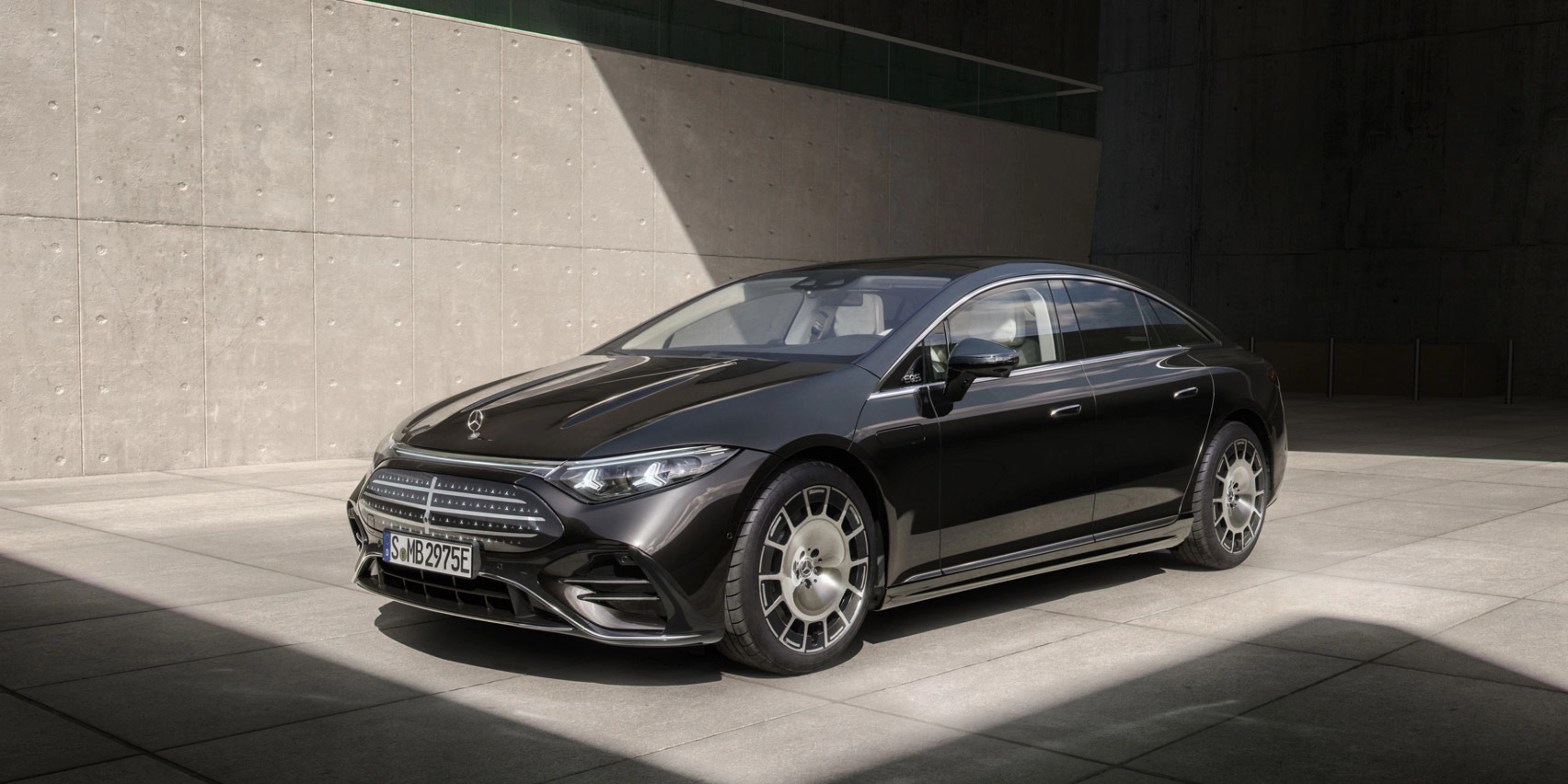 Schwarzer Mercedes-Benz steht im Sonnenlicht vor einer Betonwand