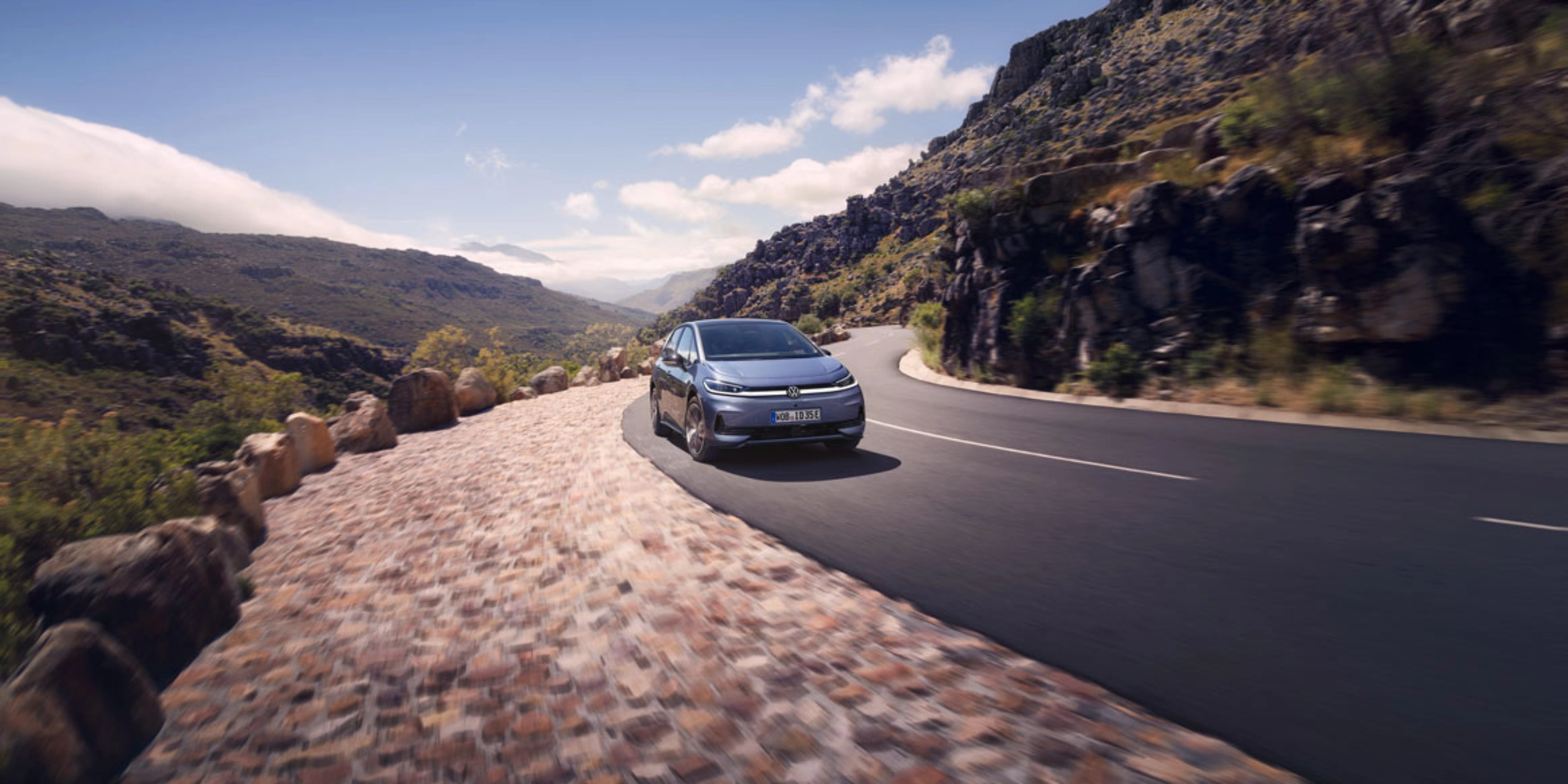 Volkswagen fährt auf einer Bergstraße mit felsiger Landschaft